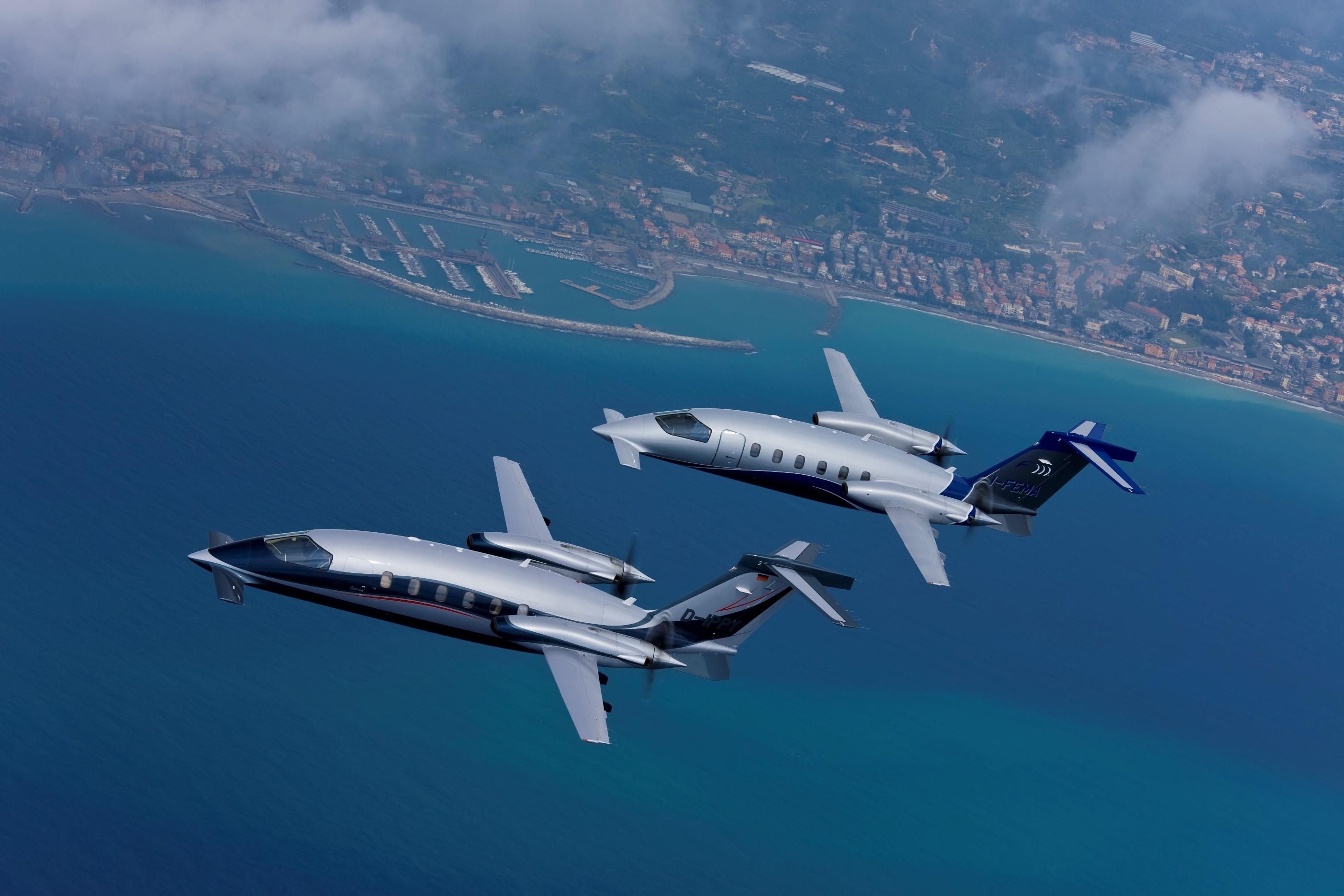 Two Piaggio P.180 Avanti aircraft flying over a coastline HD Wallpaper