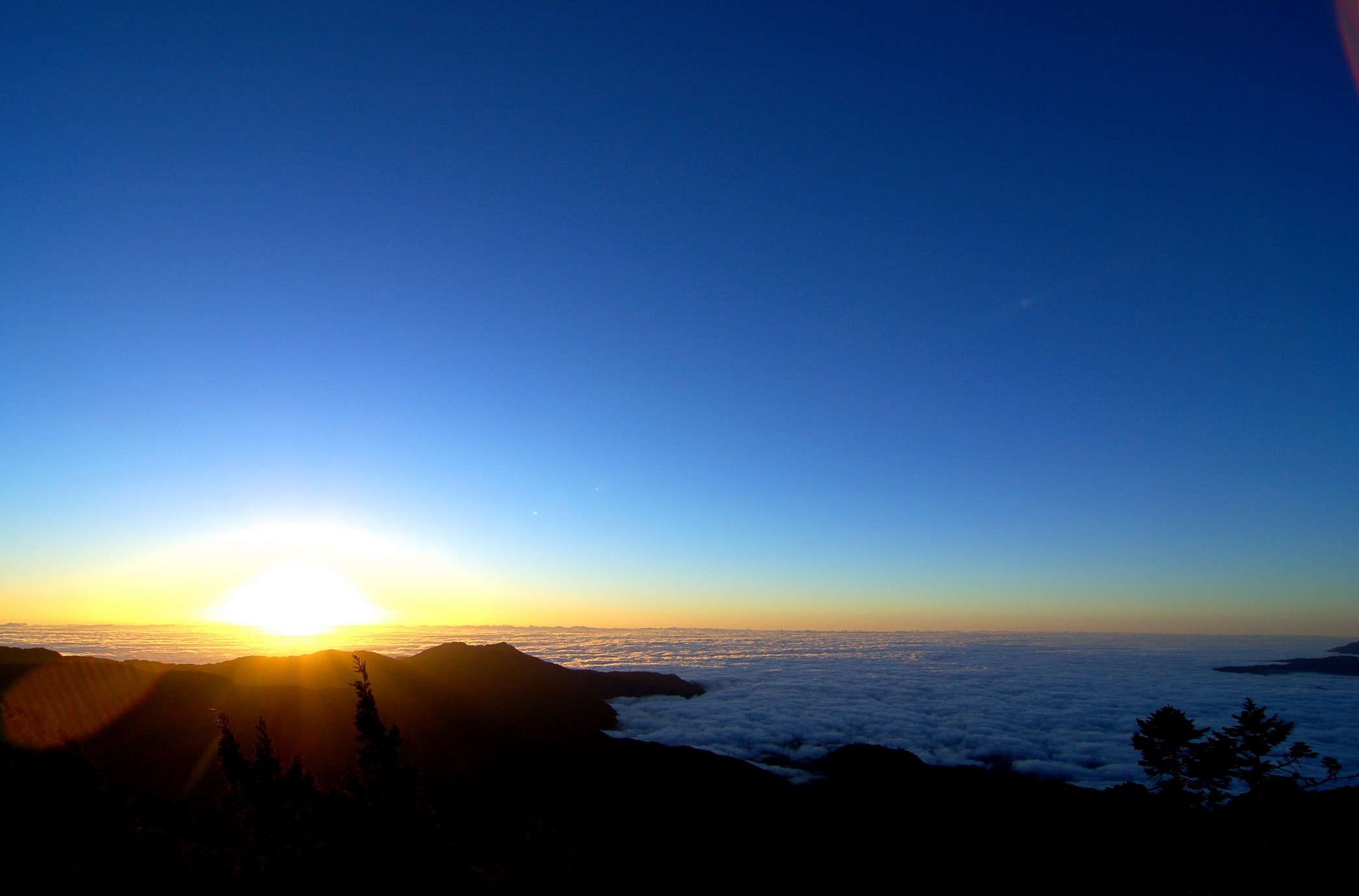 Sunrise over clouds from mountain peak HD Wallpaper