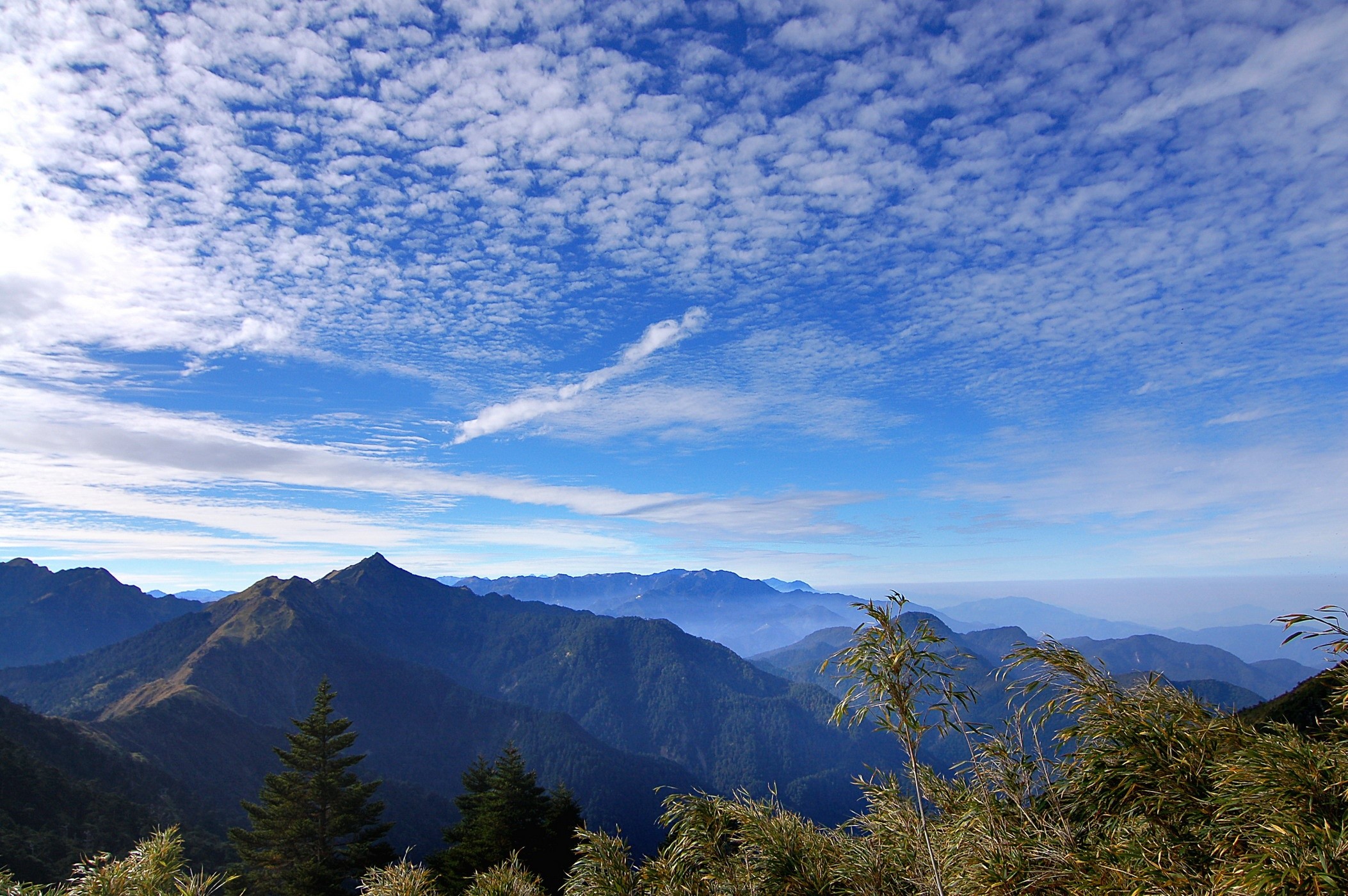 Mountain range under a cloudy blue sky HD Wallpaper