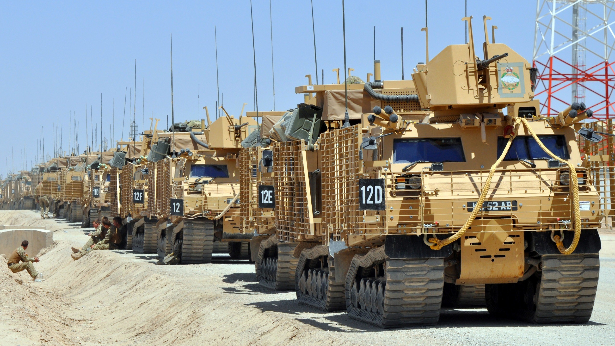 Line of military vehicles in a desert environment HD Wallpaper