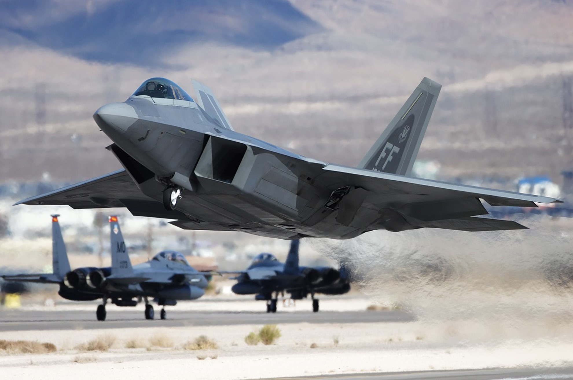 F-22 Raptor taking off with F-15 Eagles behind HD Wallpaper
