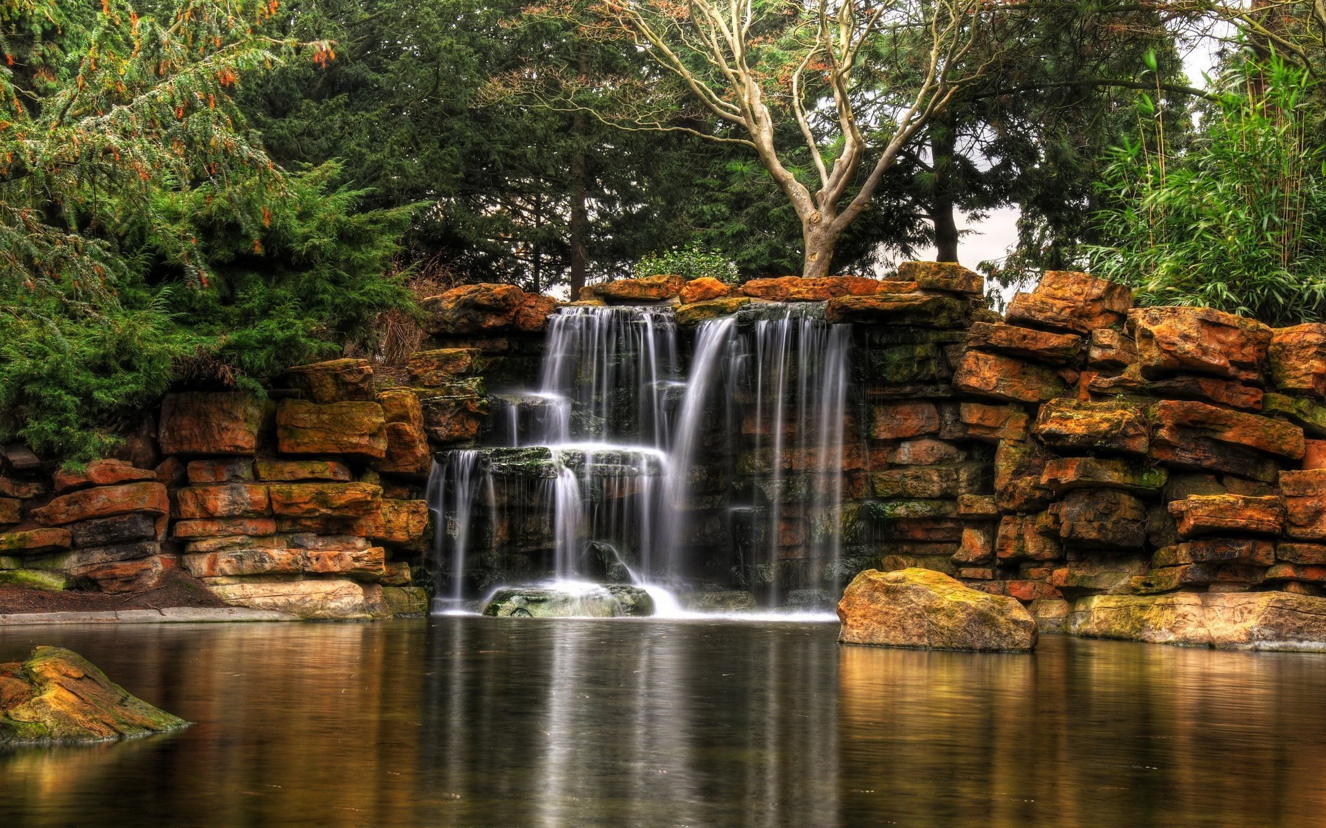 Waterfall cascading over rocks into a pond HD Wallpaper
