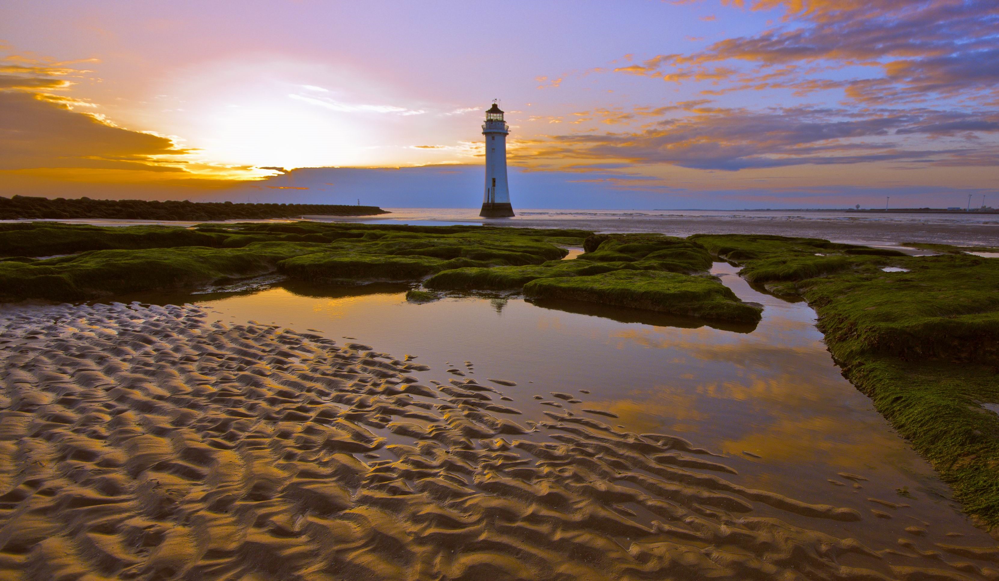 Lighthouse on a beach at sunset HD Wallpaper