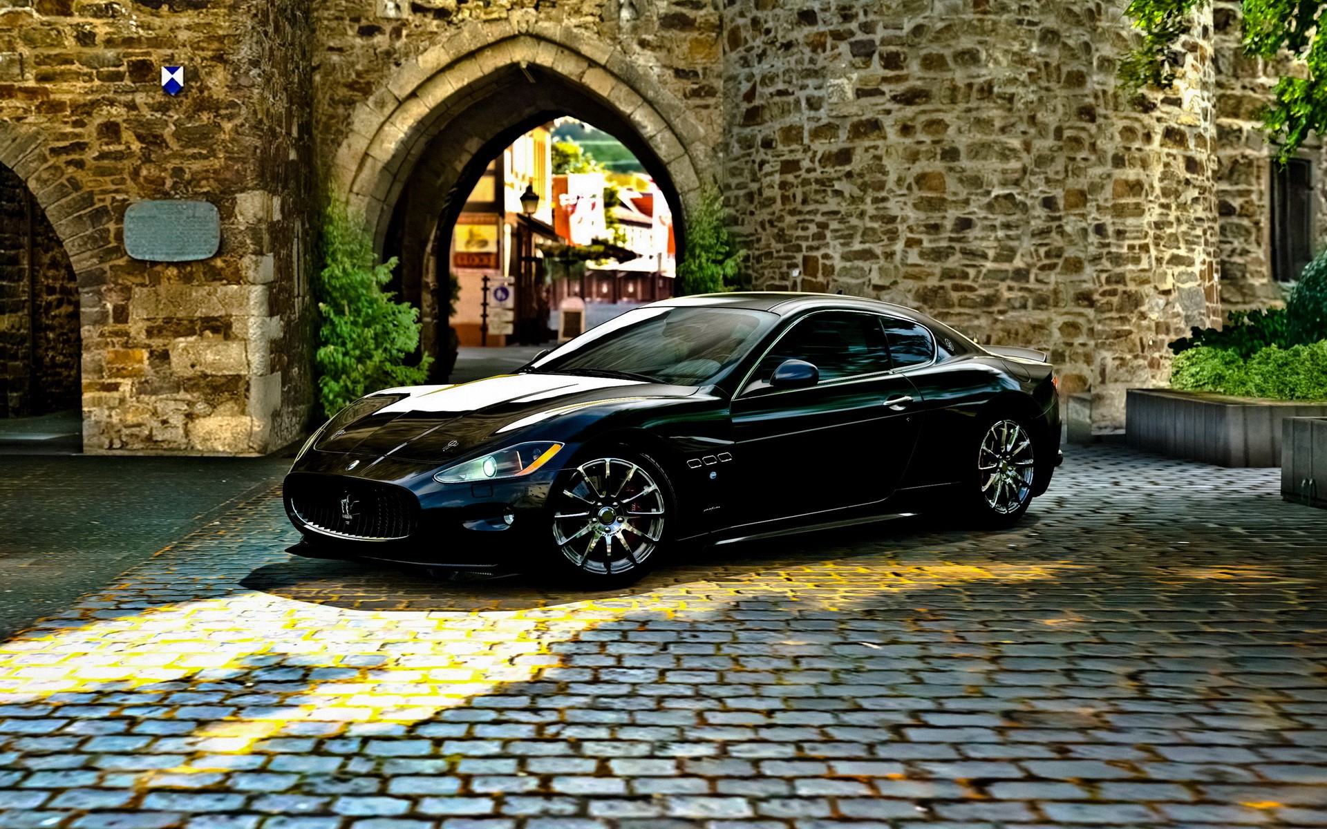 Black Maserati GranTurismo parked under stone archway HD Wallpaper