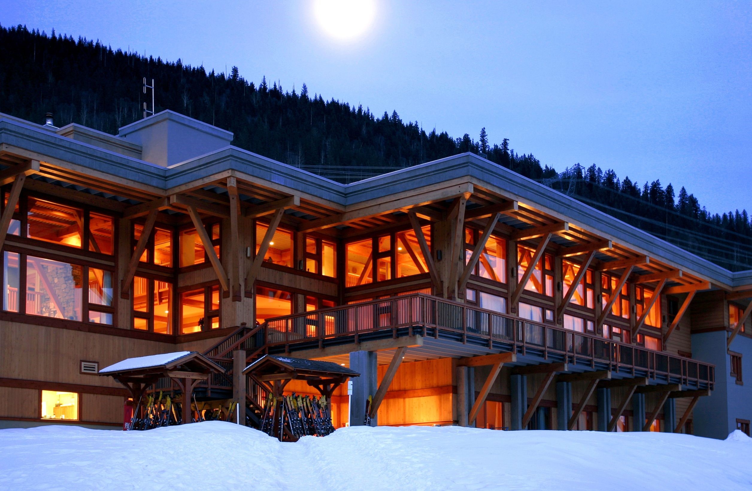 Wooden lodge with ski equipment in snow at dusk HD Wallpaper