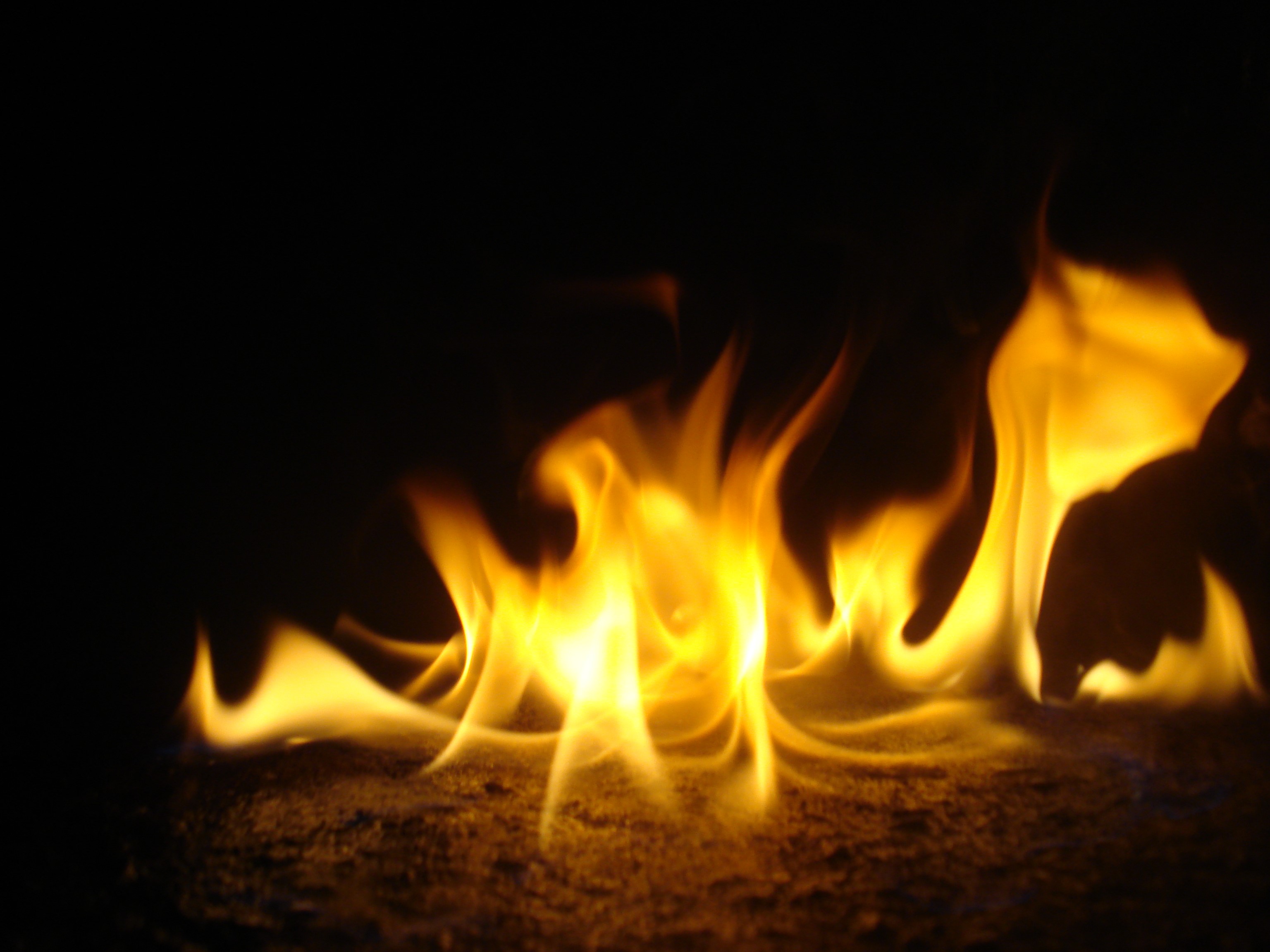 Close-up of bright orange flames on a dark background HD Wallpaper