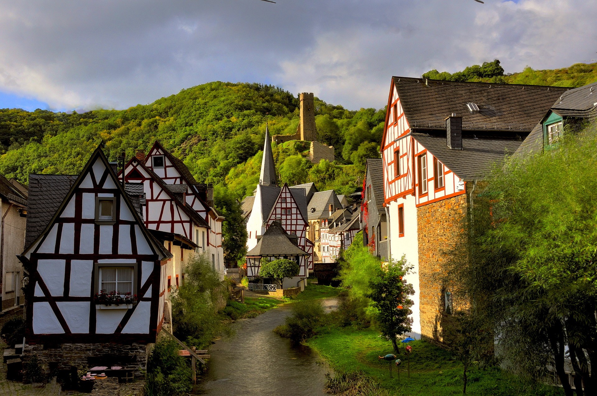 Half-timbered houses along a river in Germany with a castle ruin HD Wallpaper