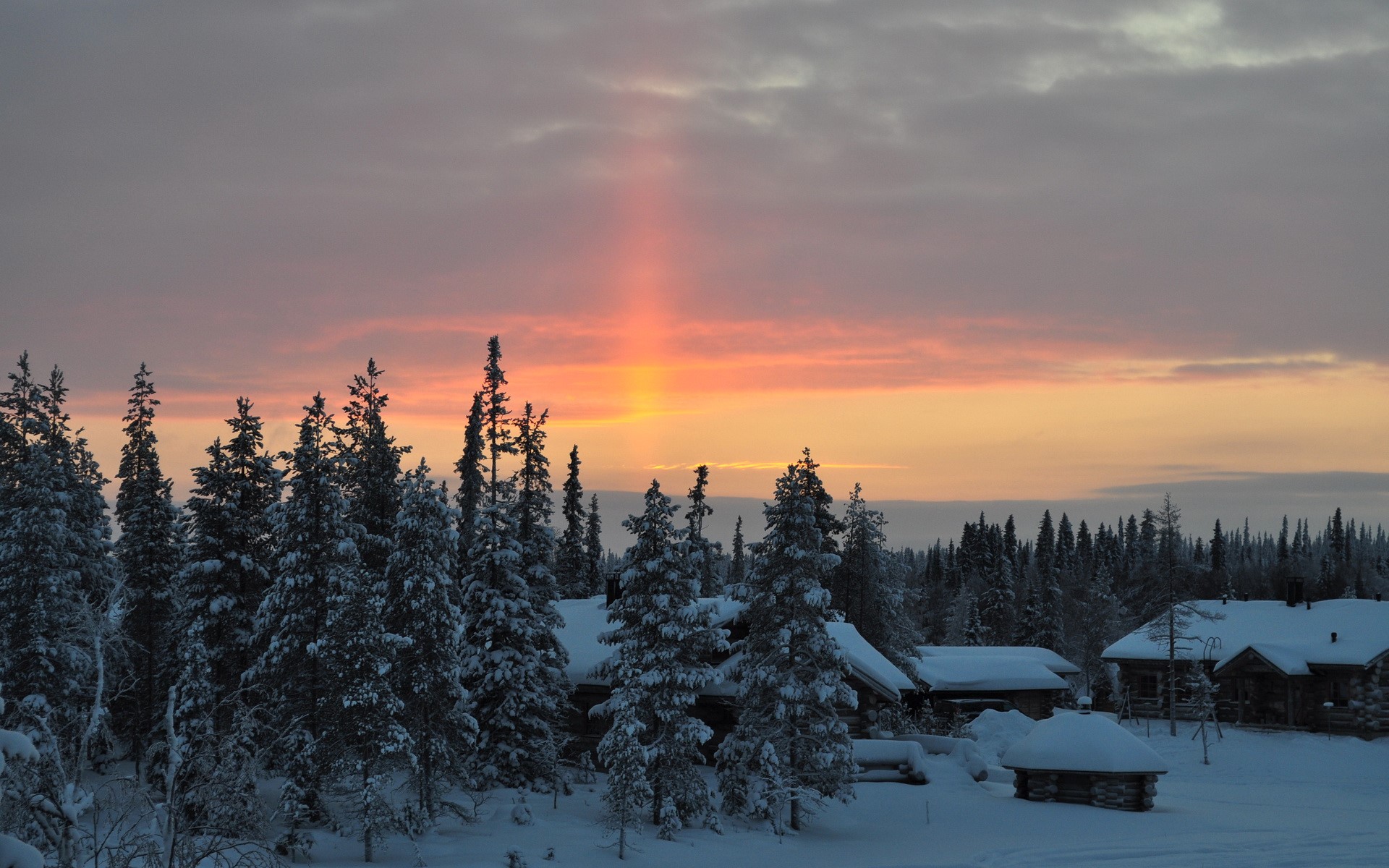 Winter sunset over snowy cabins and pine forest HD Wallpaper