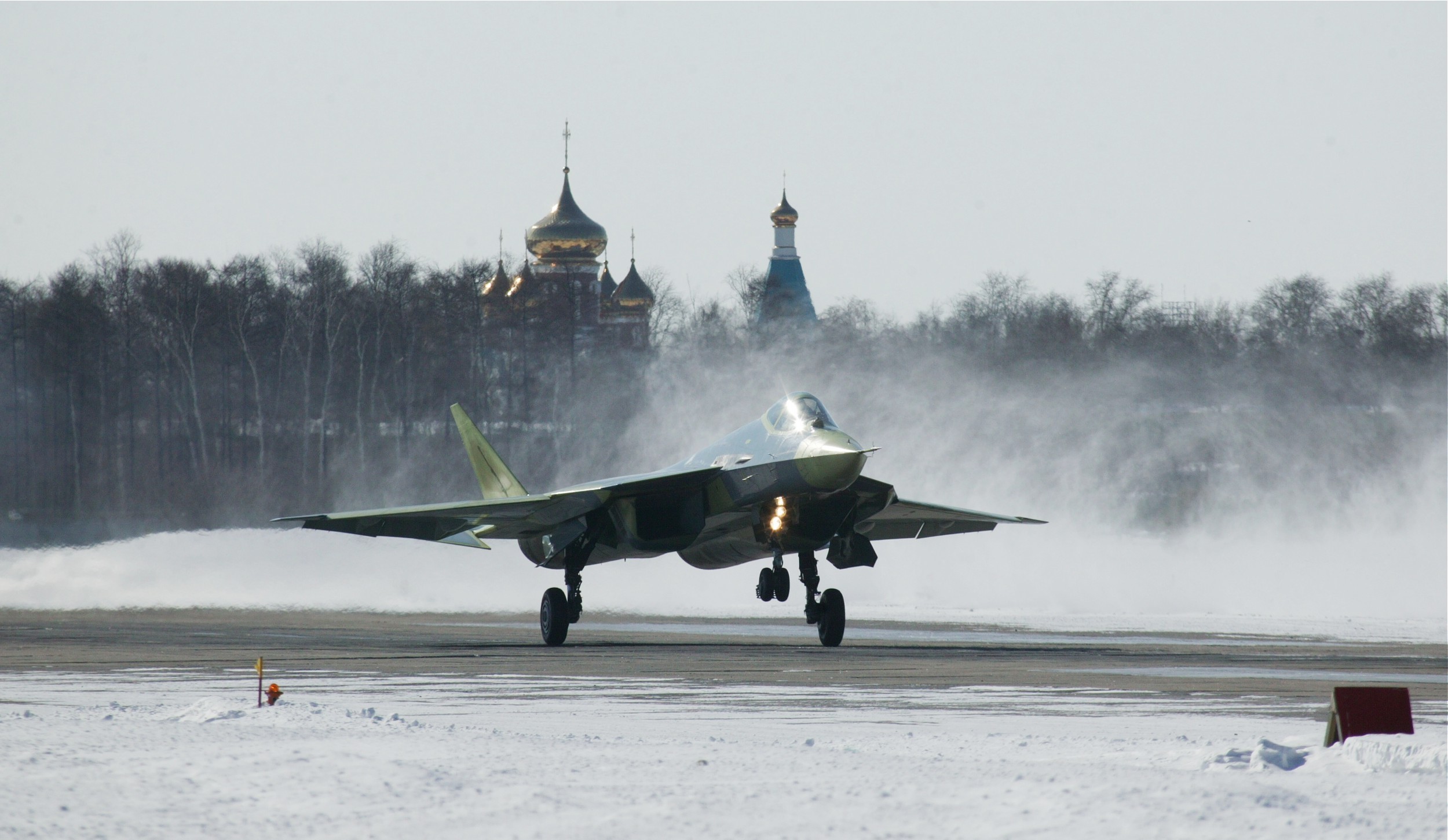 Sukhoi Su-57 fighter jet on a snowy runway HD Wallpaper