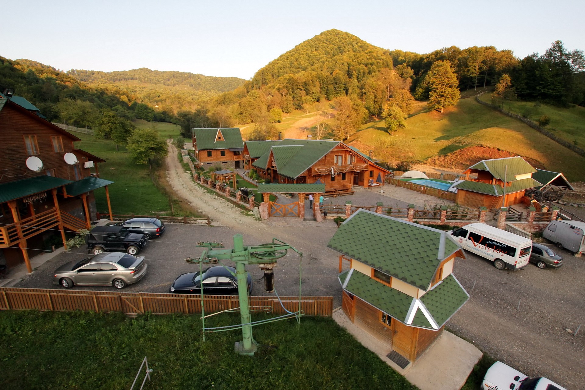 Wooden houses and cars in a mountain landscape HD Wallpaper