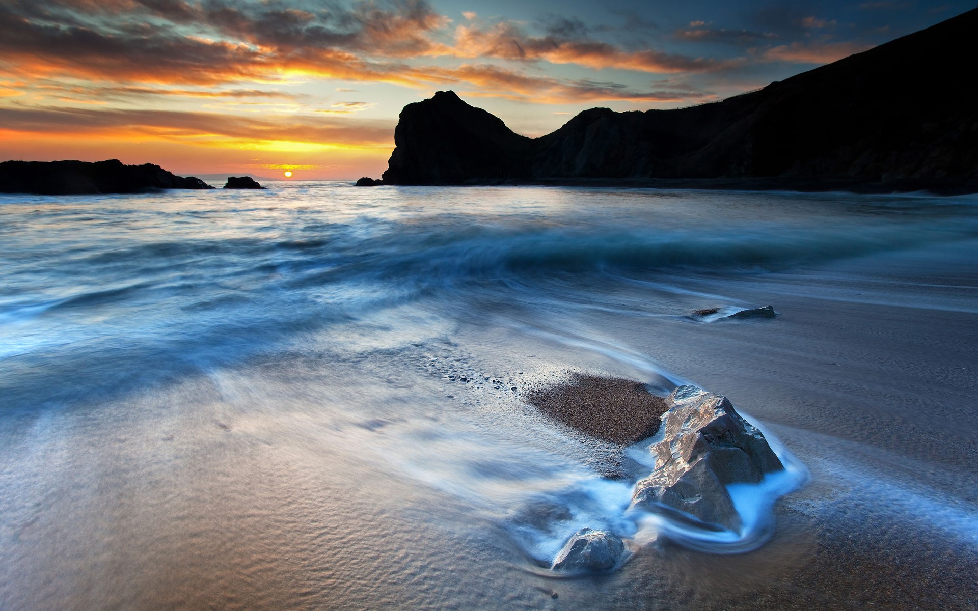 Sunset over a rocky beach with waves HD Wallpaper