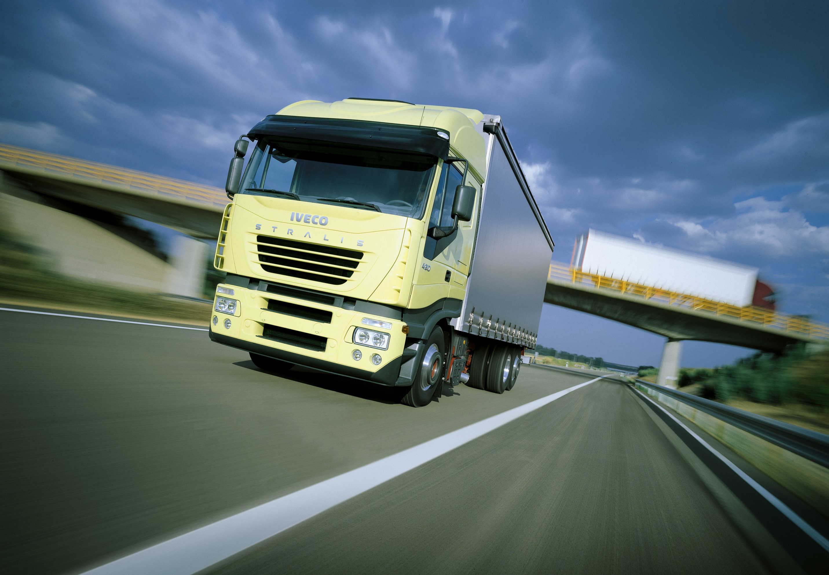 Yellow Iveco Stralis truck on a highway HD Wallpaper