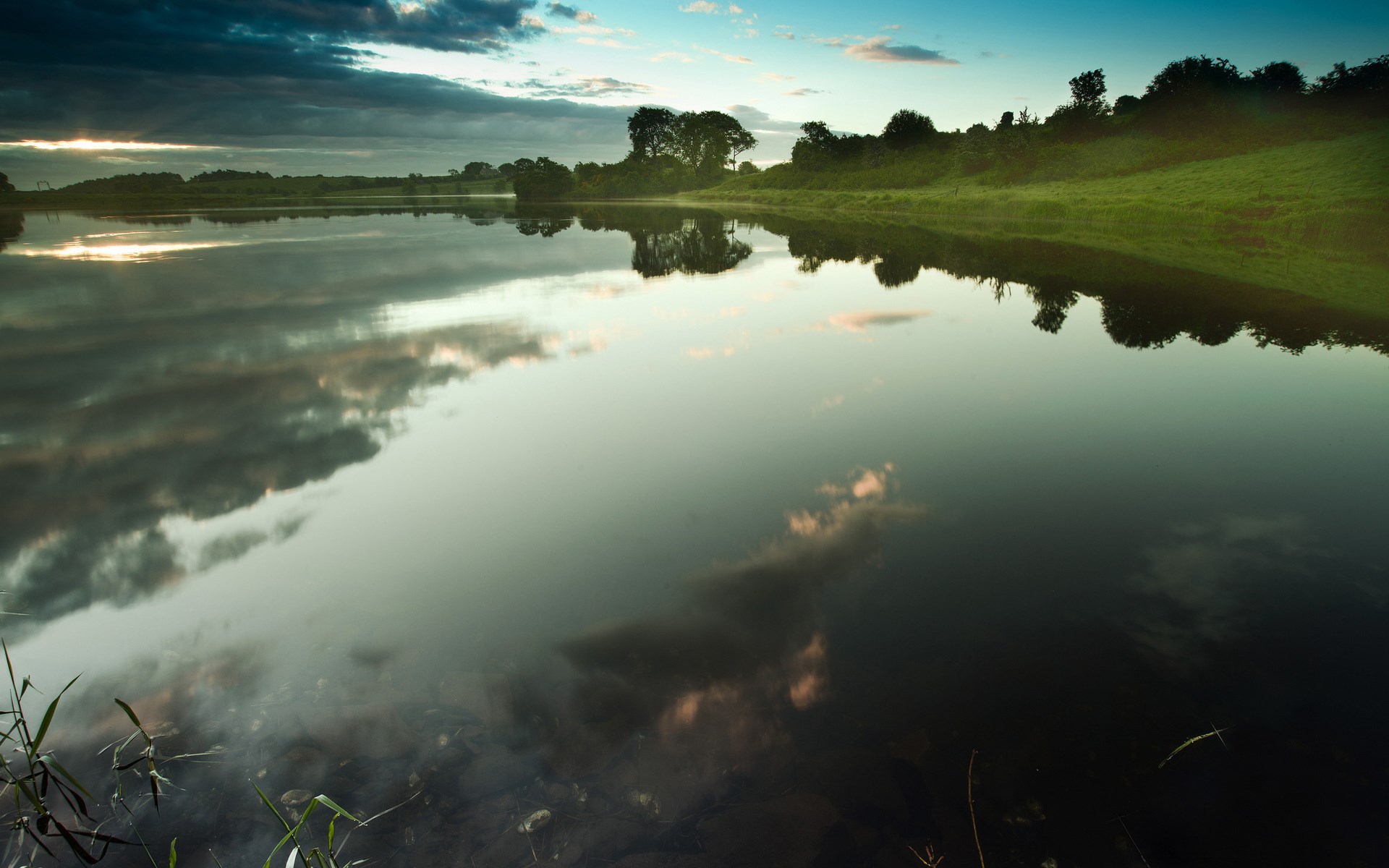 Calm lake reflecting trees and clouds at sunrise HD Wallpaper