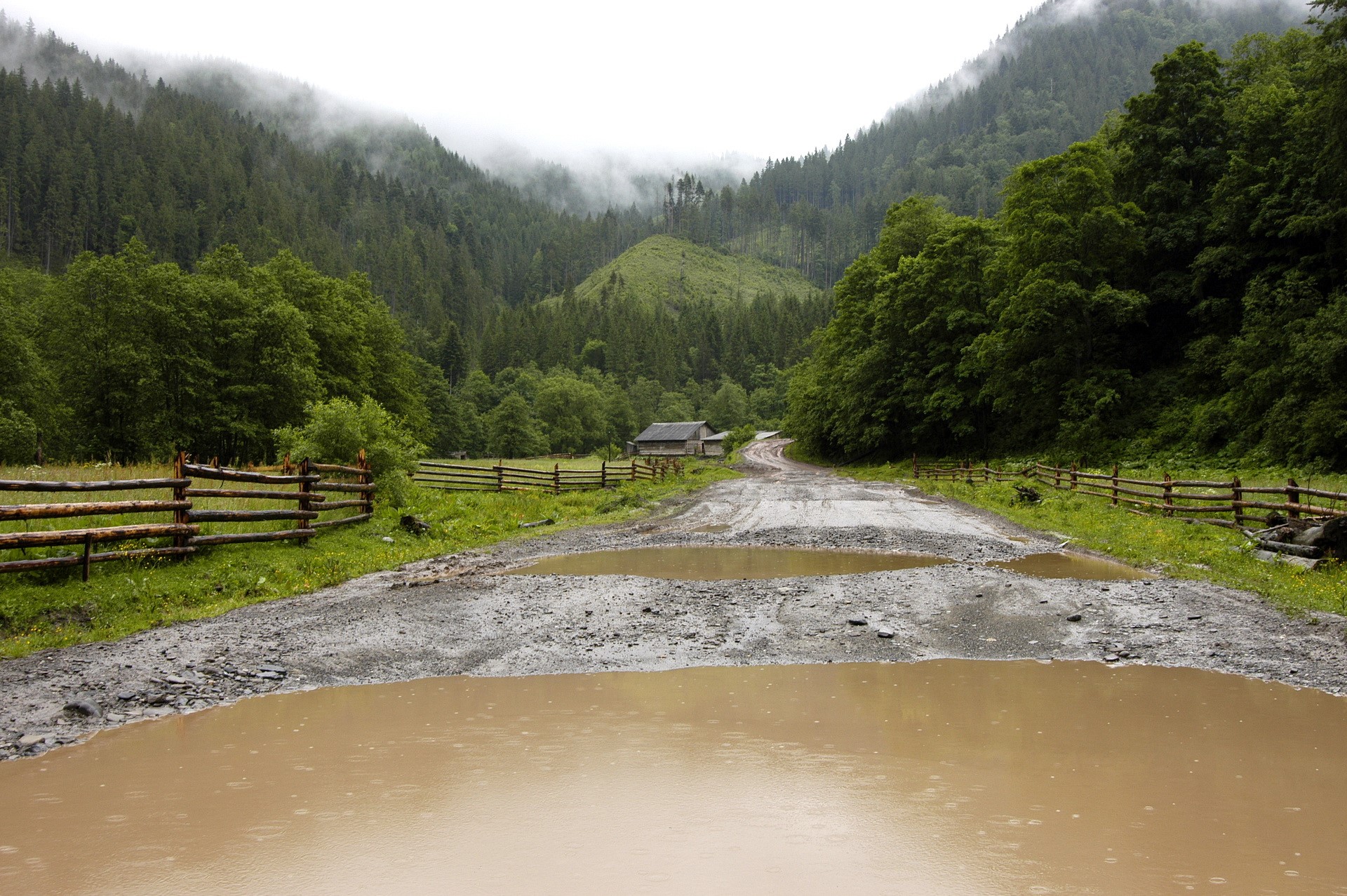 Dirt road with puddles in a mountain valley HD Wallpaper