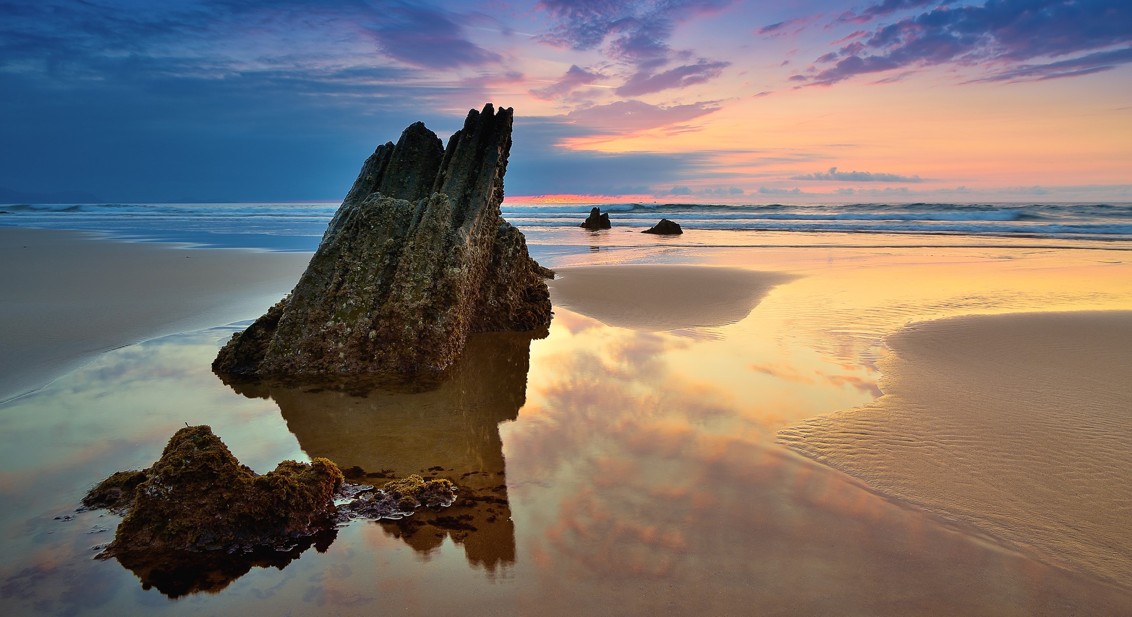 Beach rock formation at sunset with ocean waves HD Wallpaper