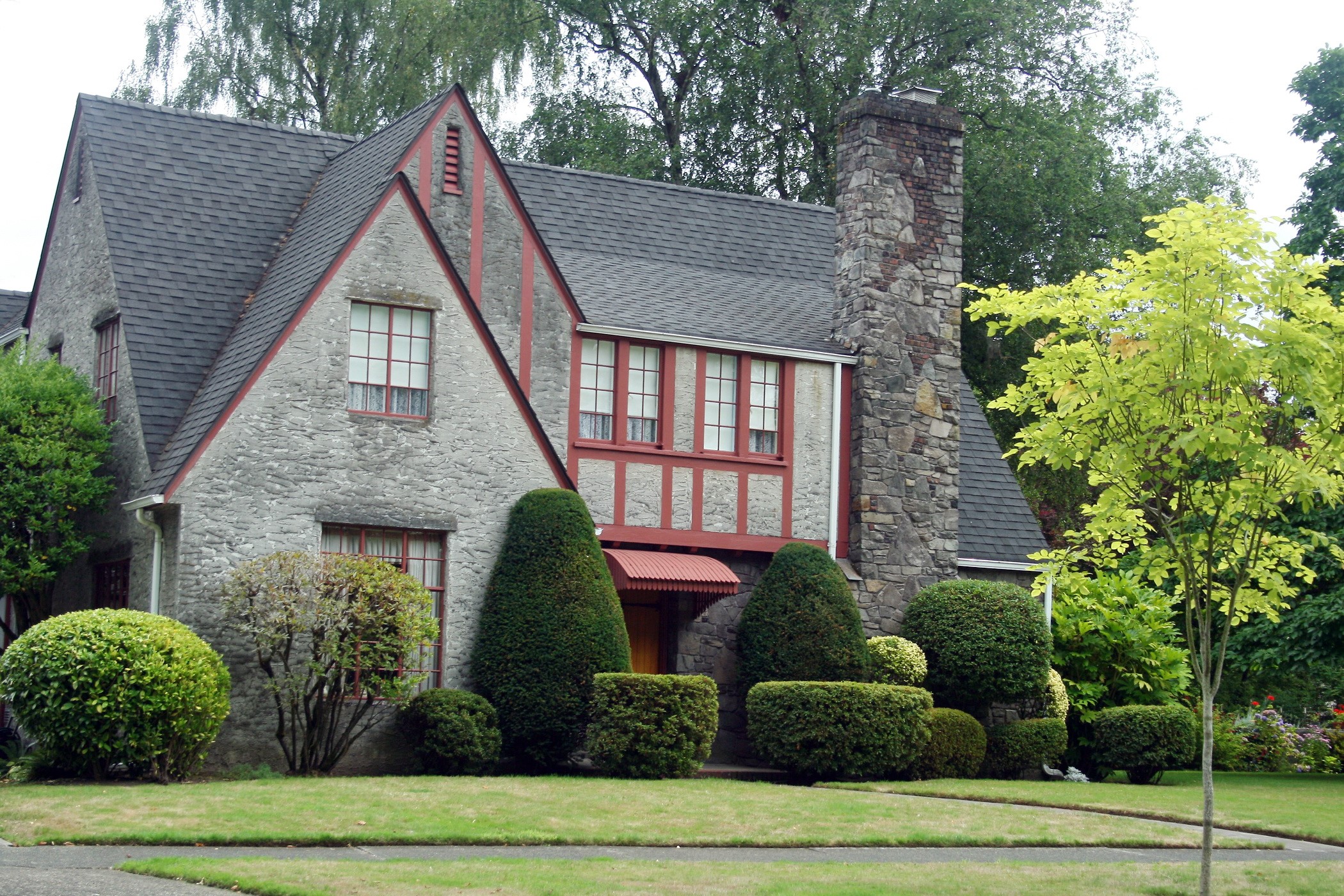Stone house with manicured bushes and trees HD Wallpaper