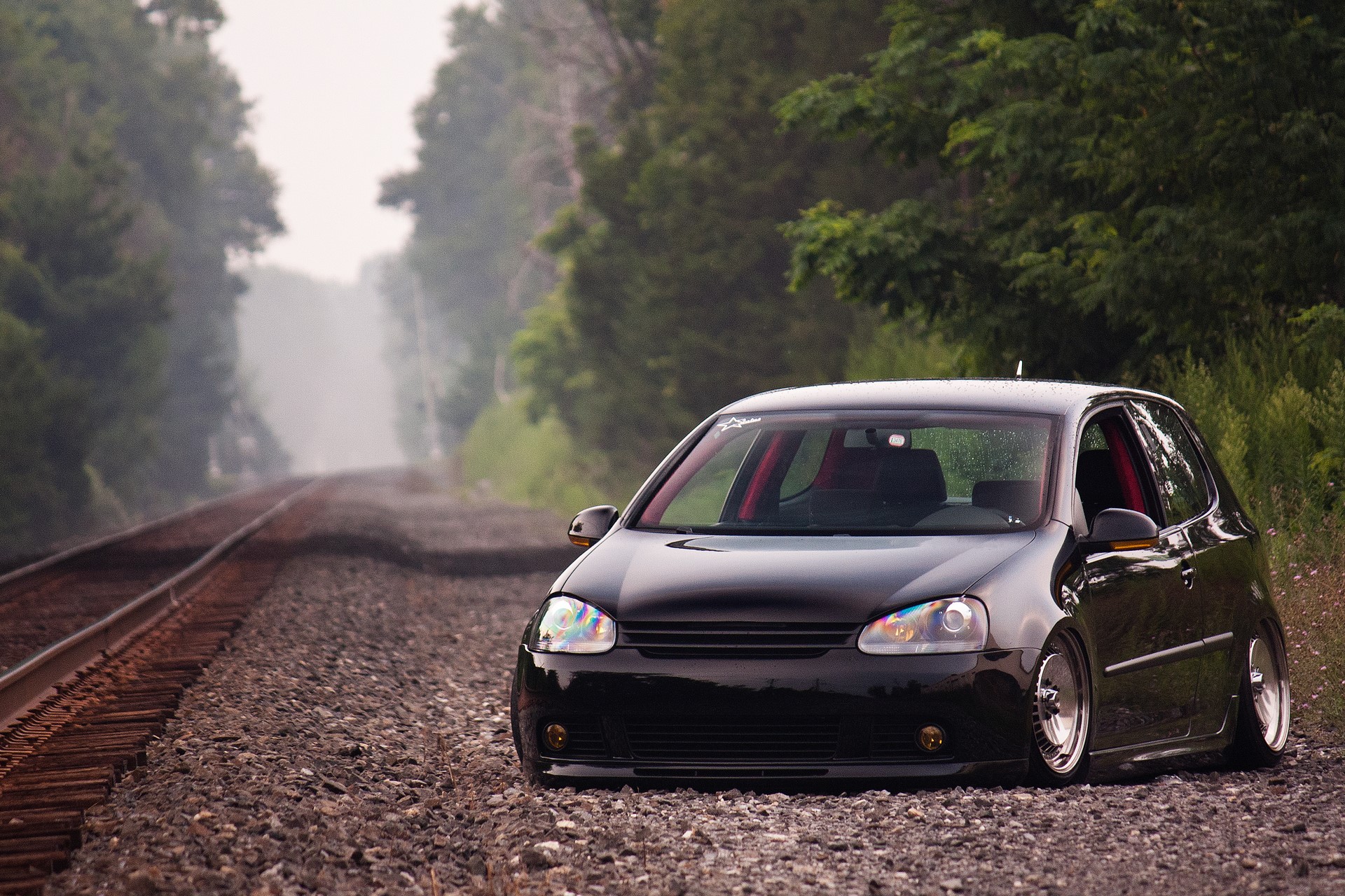 Black Volkswagen Golf GTI parked on train tracks HD Wallpaper