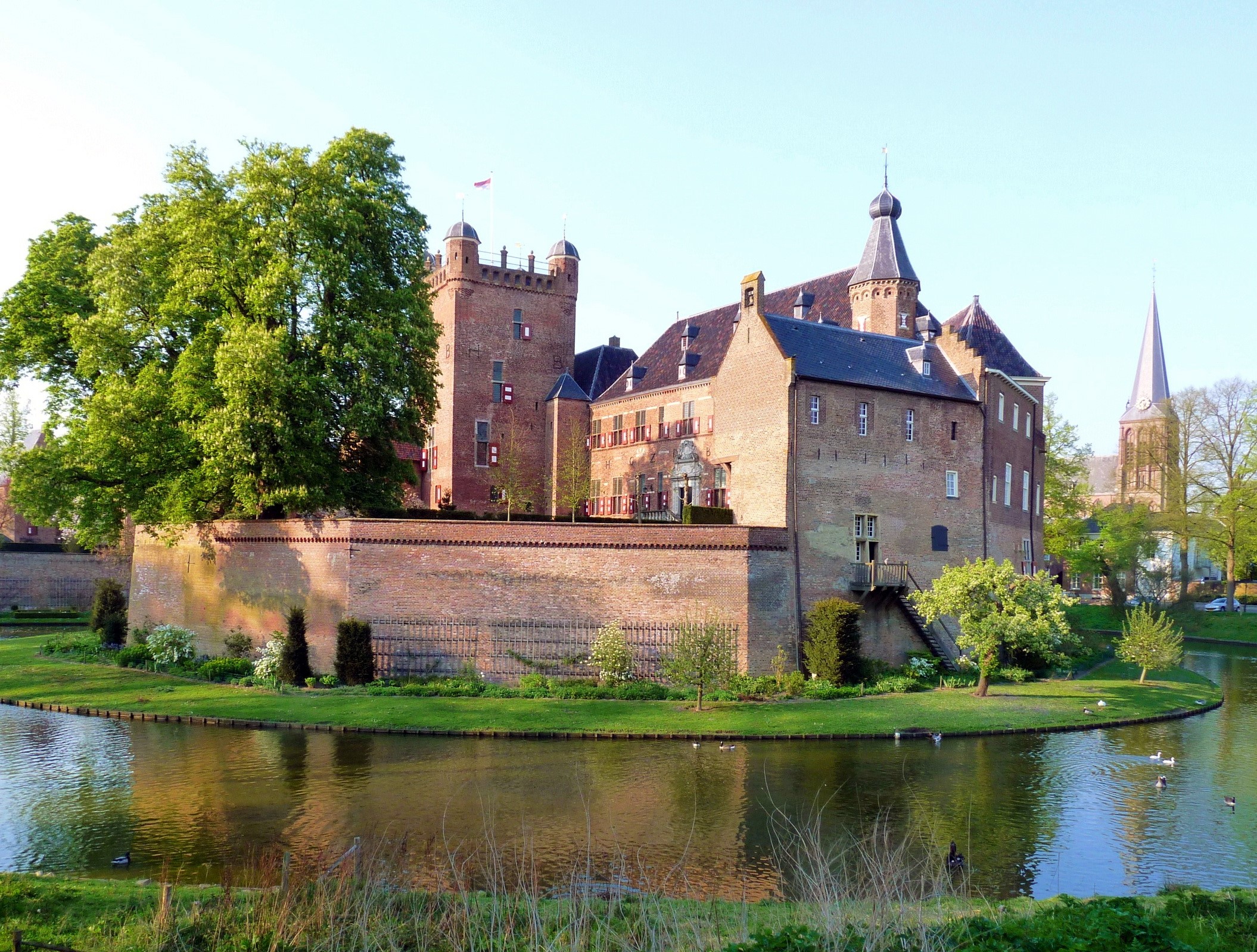 Castle surrounded by a moat with a church in the background HD Wallpaper
