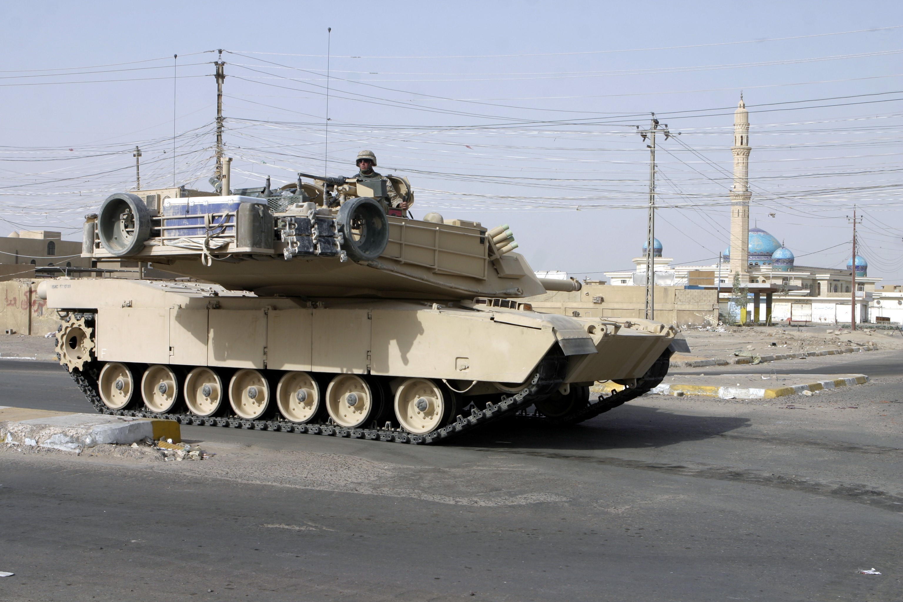 M1 Abrams tank with soldier in desert city HD Wallpaper
