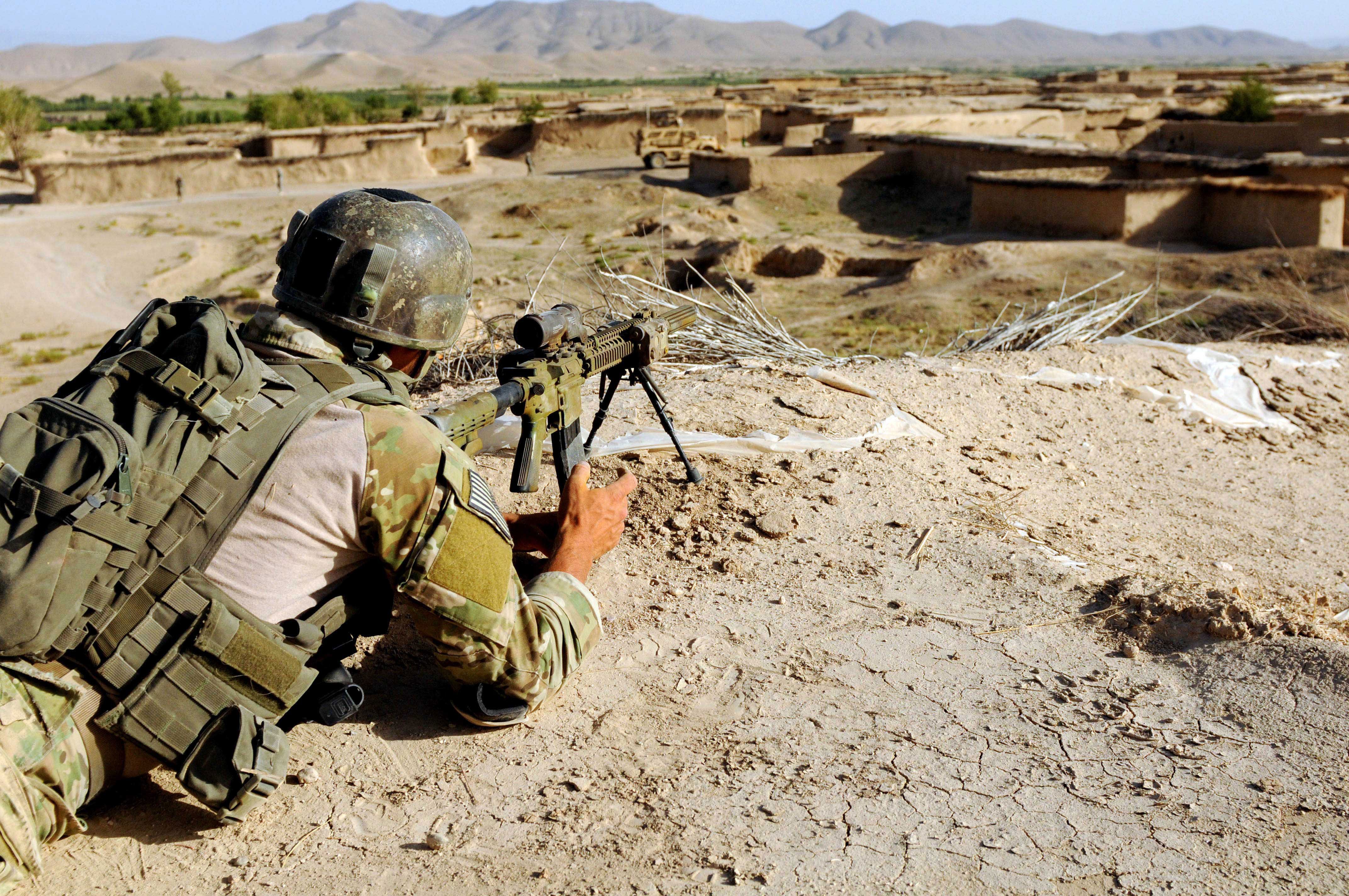 Soldier aiming a rifle in a village HD Wallpaper
