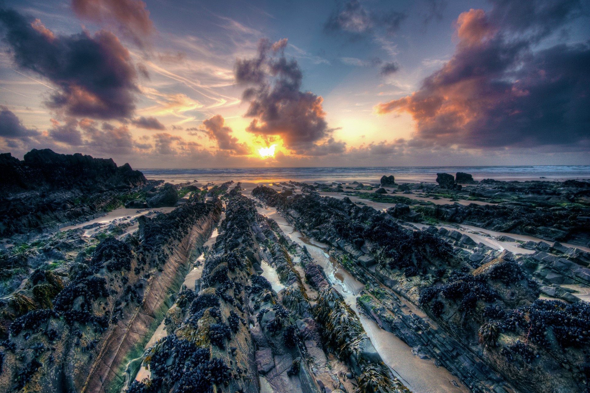 Rocky beach at sunset with dramatic clouds HD Wallpaper