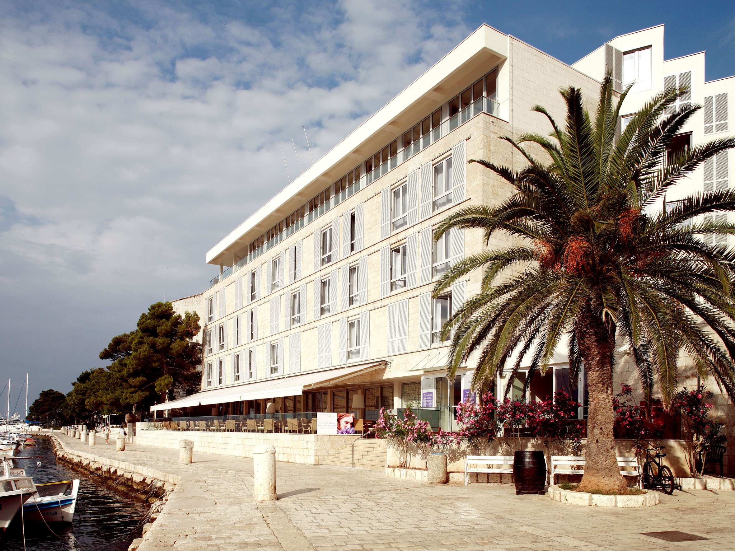 Hotel building with palm tree and boats by the water HD Wallpaper