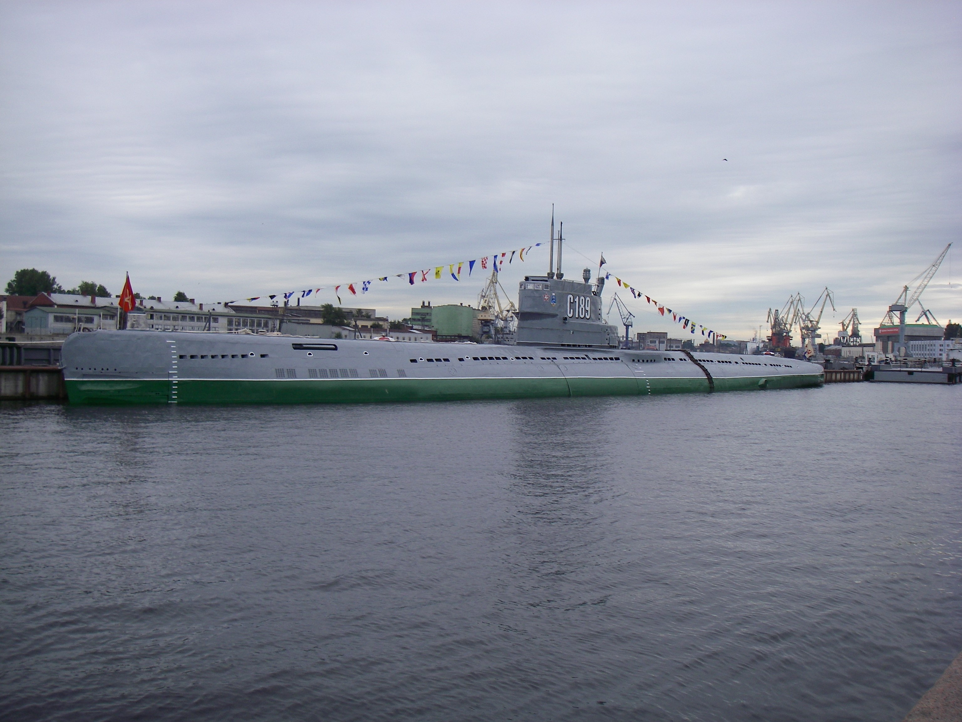 Submarine C189 docked in a harbor with cranes HD Wallpaper
