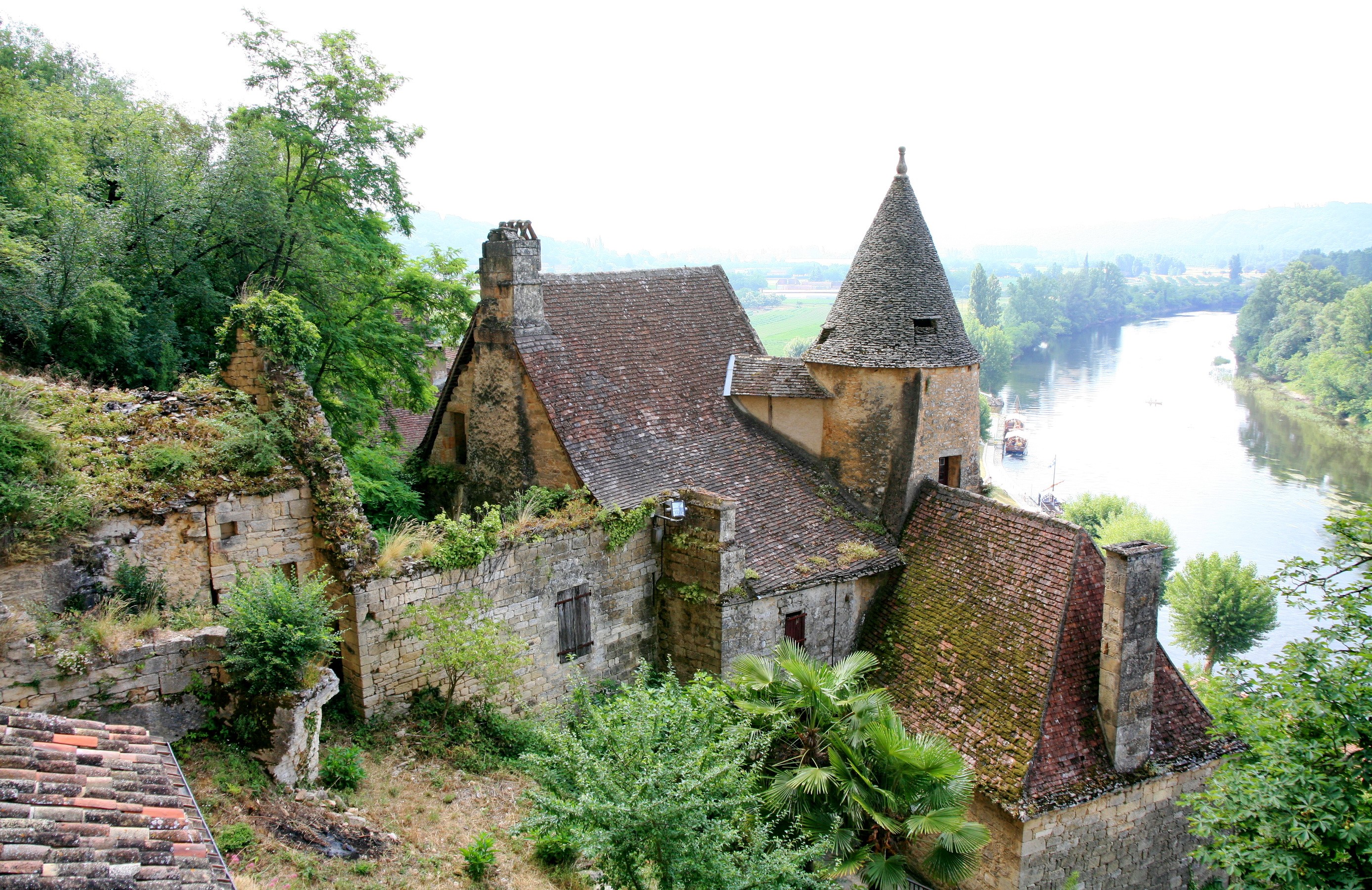 Stone buildings with conical tower overlooking a river HD Wallpaper
