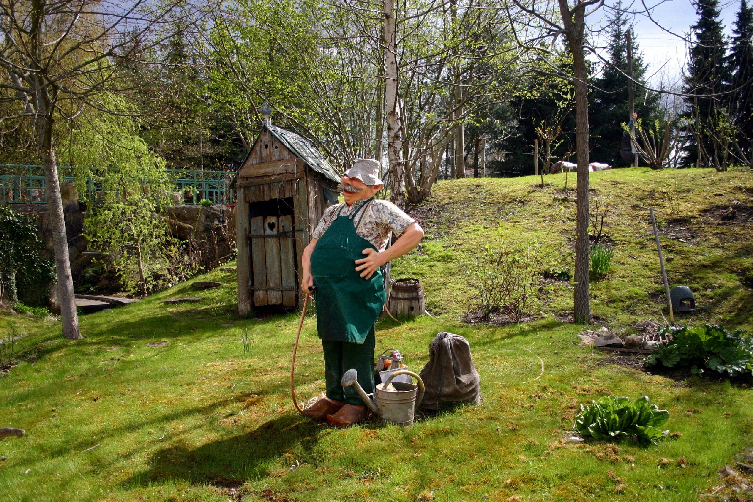 Garden gnome with watering can near outhouse HD Wallpaper