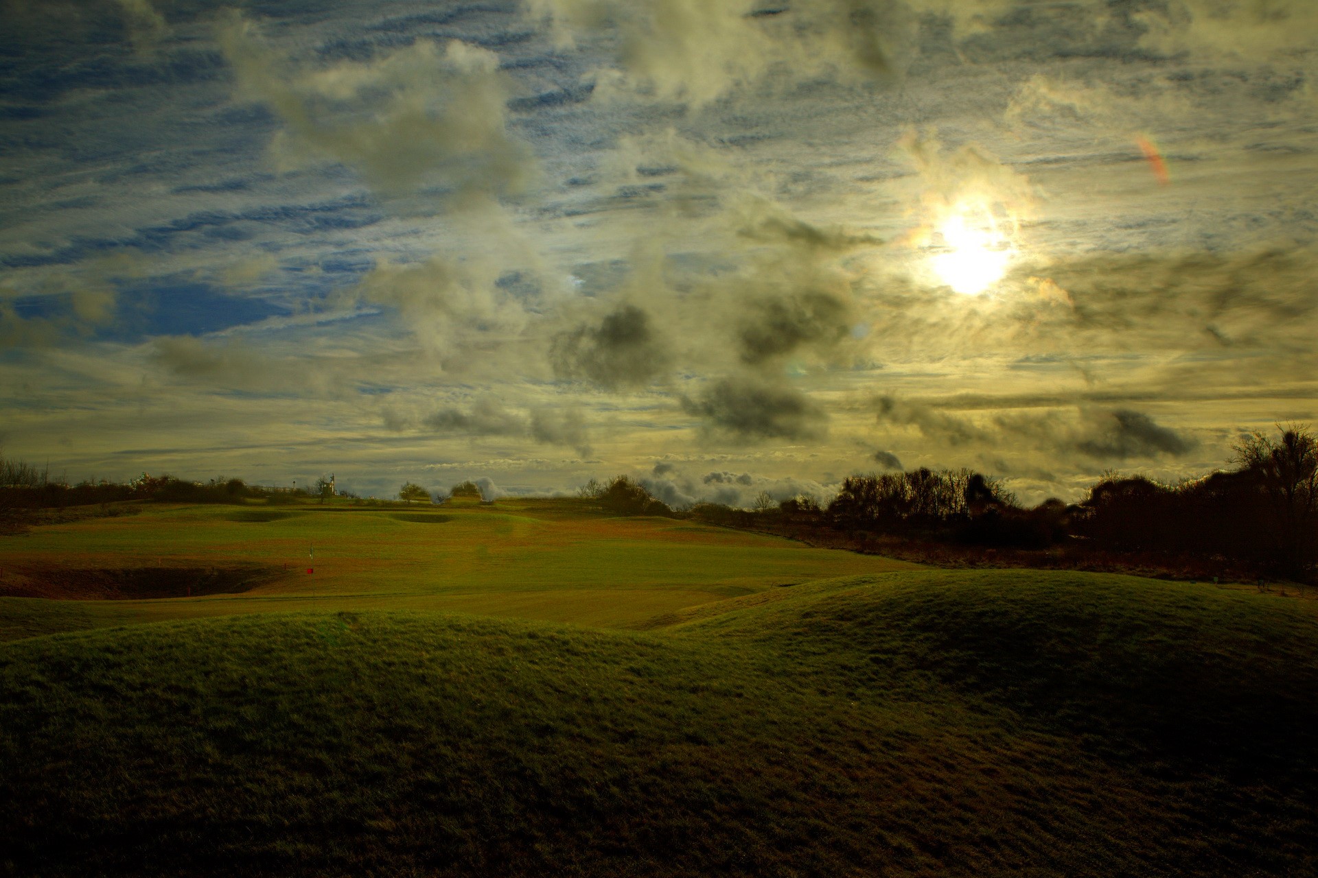 Golf course with dramatic cloudy sky at sunset HD Wallpaper