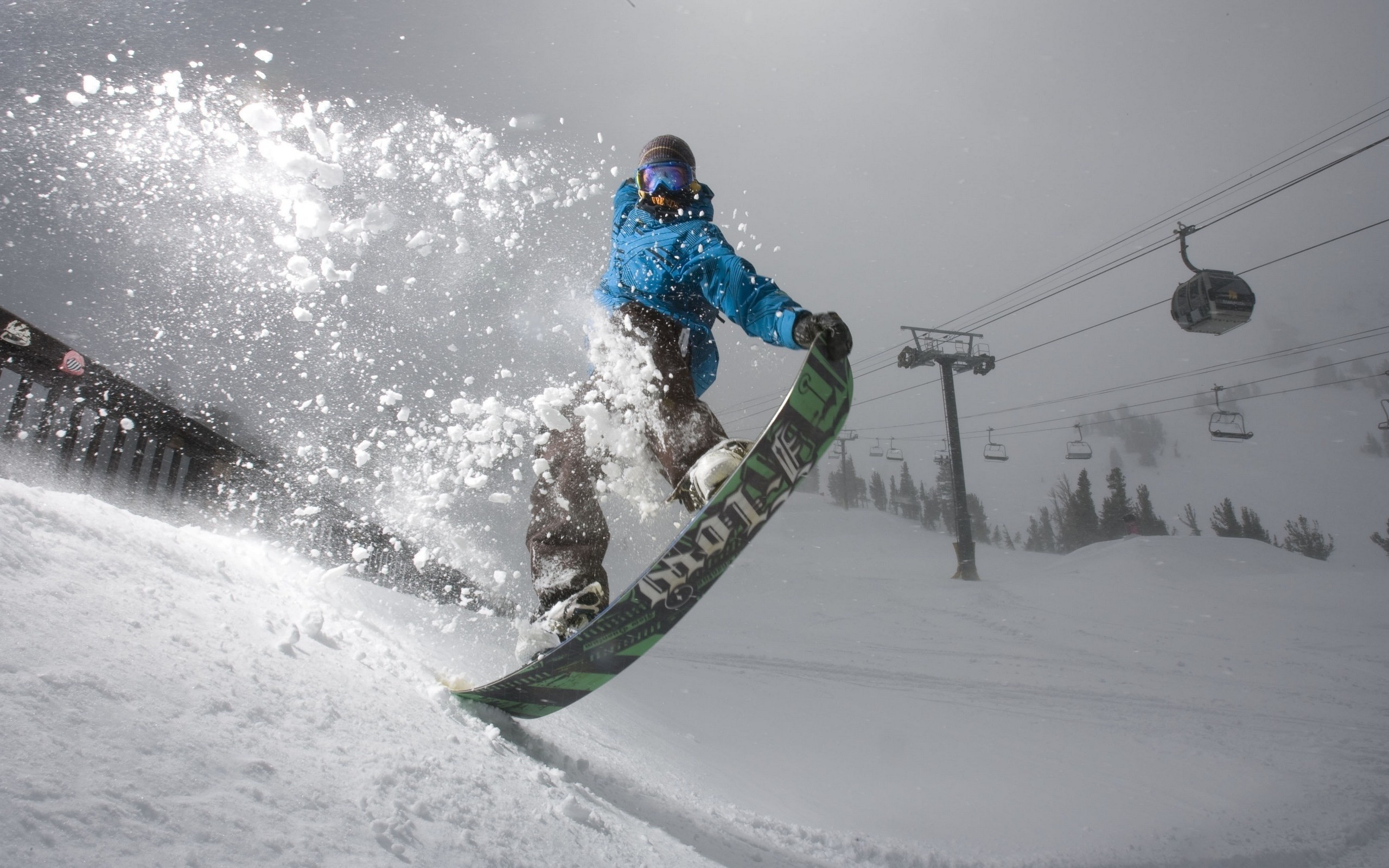 Snowboarder jumping with snow spray and ski lift HD Wallpaper