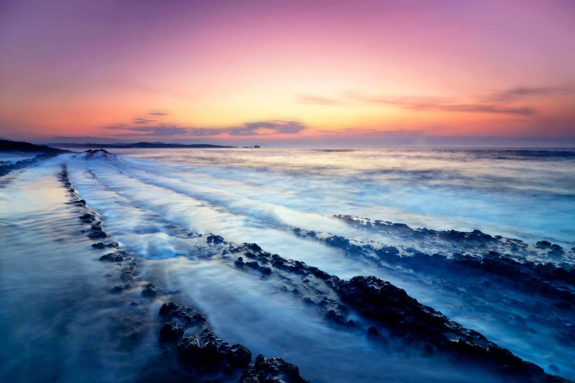 Ocean waves crashing on rocky shore at sunset HD Wallpaper