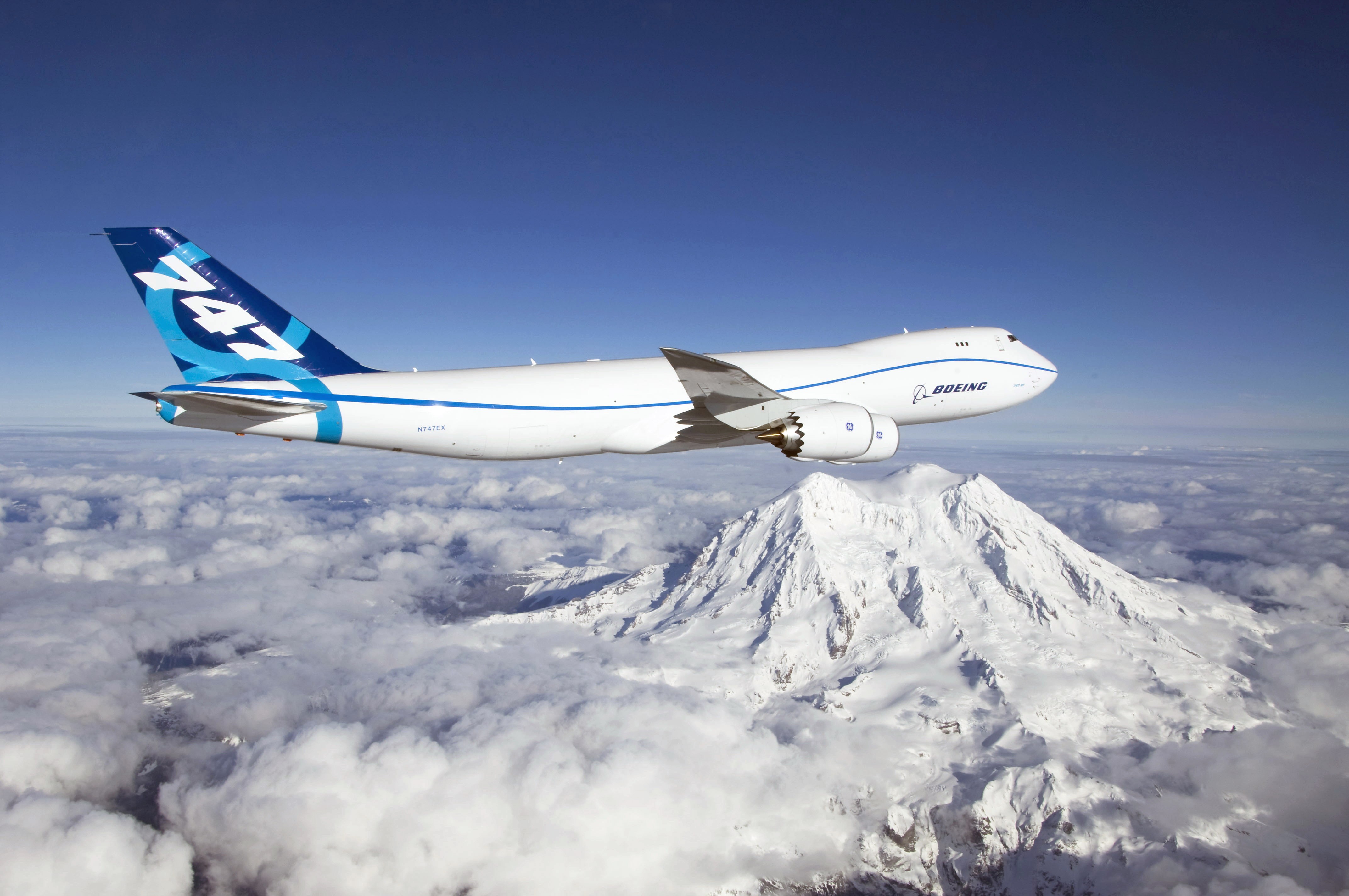 Boeing 747-8F cargo plane flying over mountains HD Wallpaper