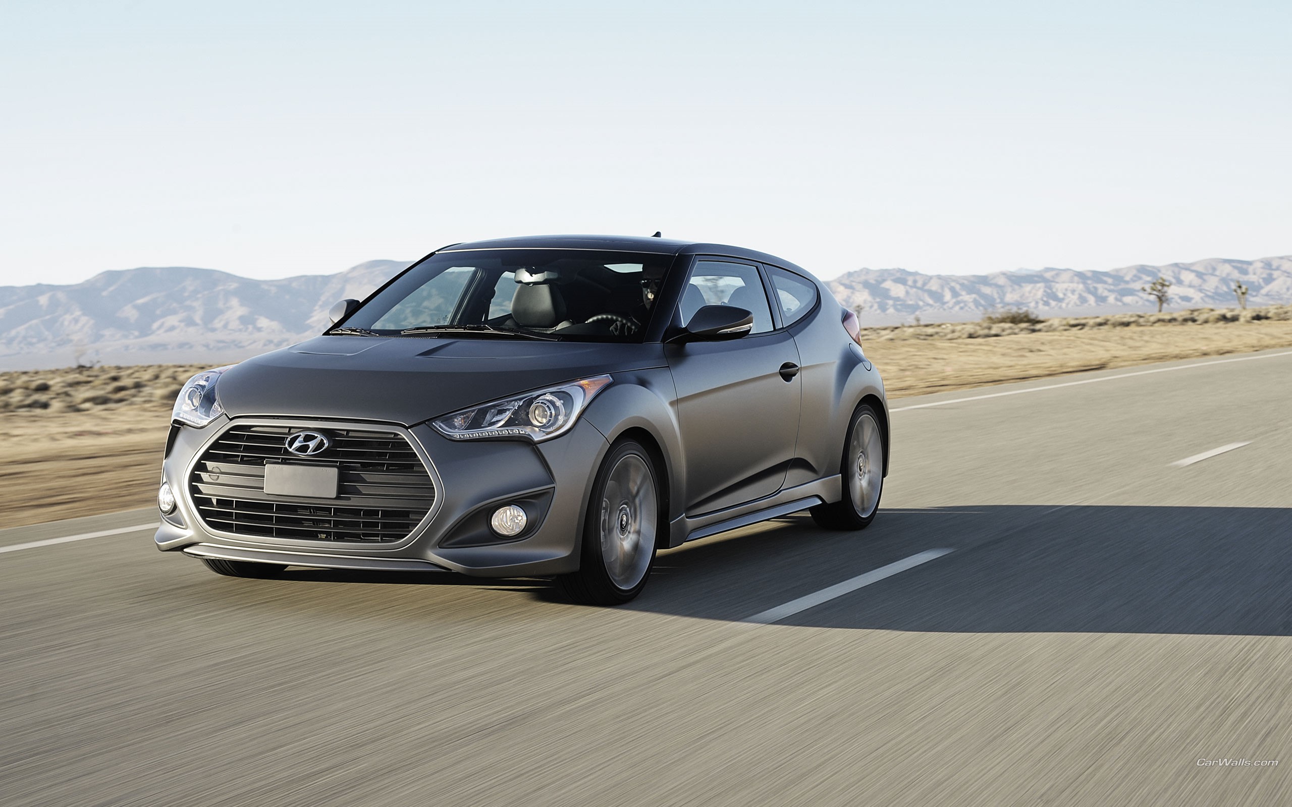 Hyundai Veloster driving on a desert road HD Wallpaper