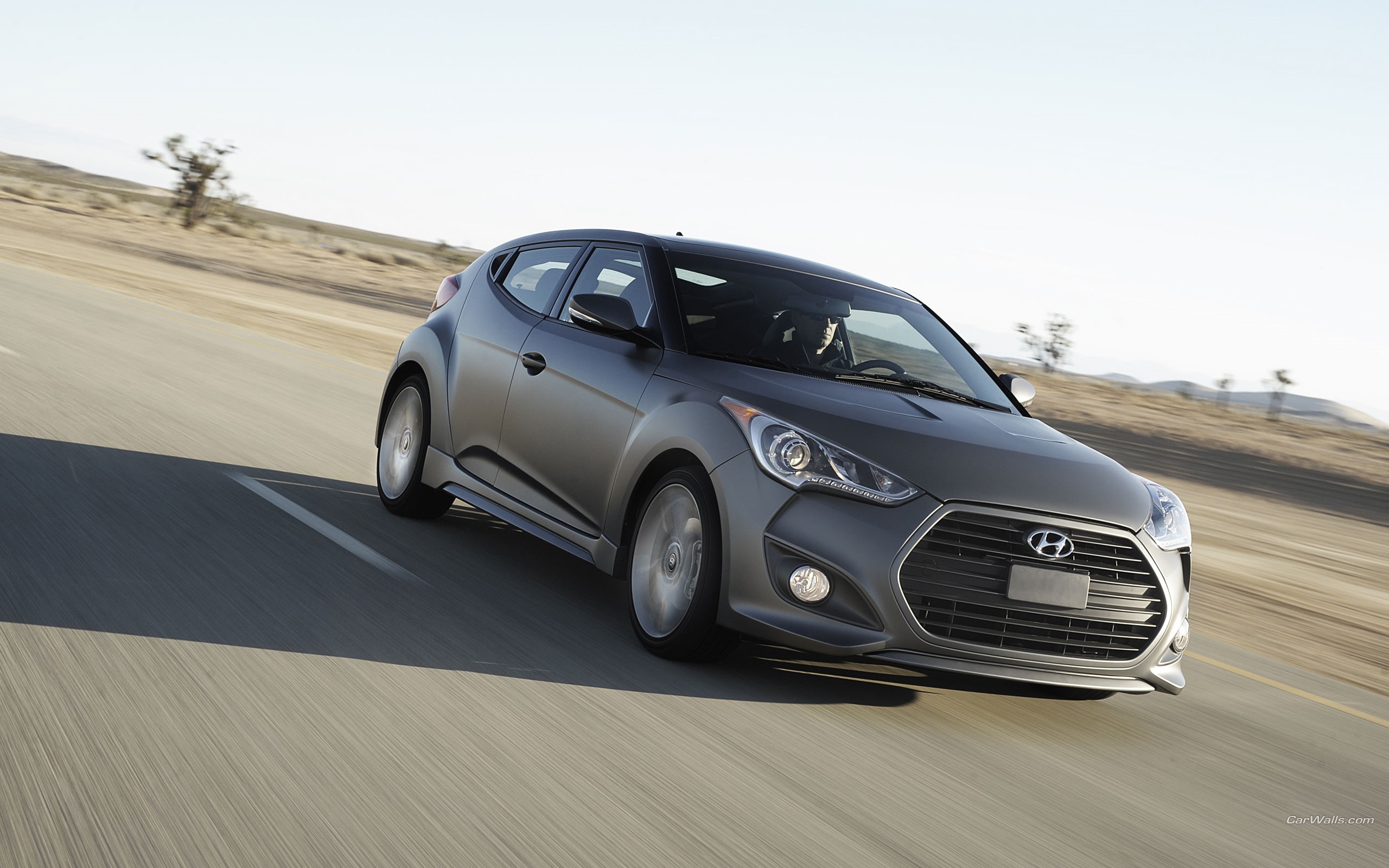 Hyundai Veloster driving on a desert road HD Wallpaper