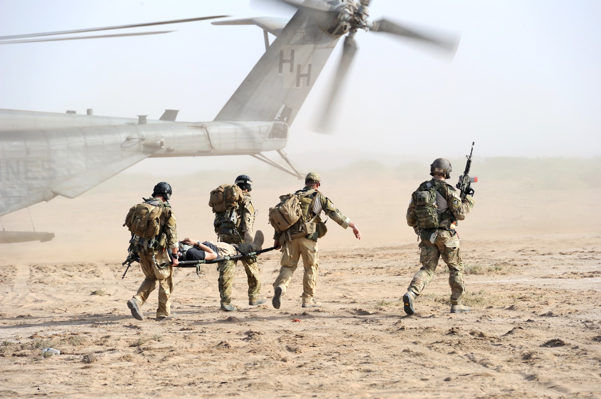 Soldiers carrying a casualty on a stretcher near a helicopter HD Wallpaper