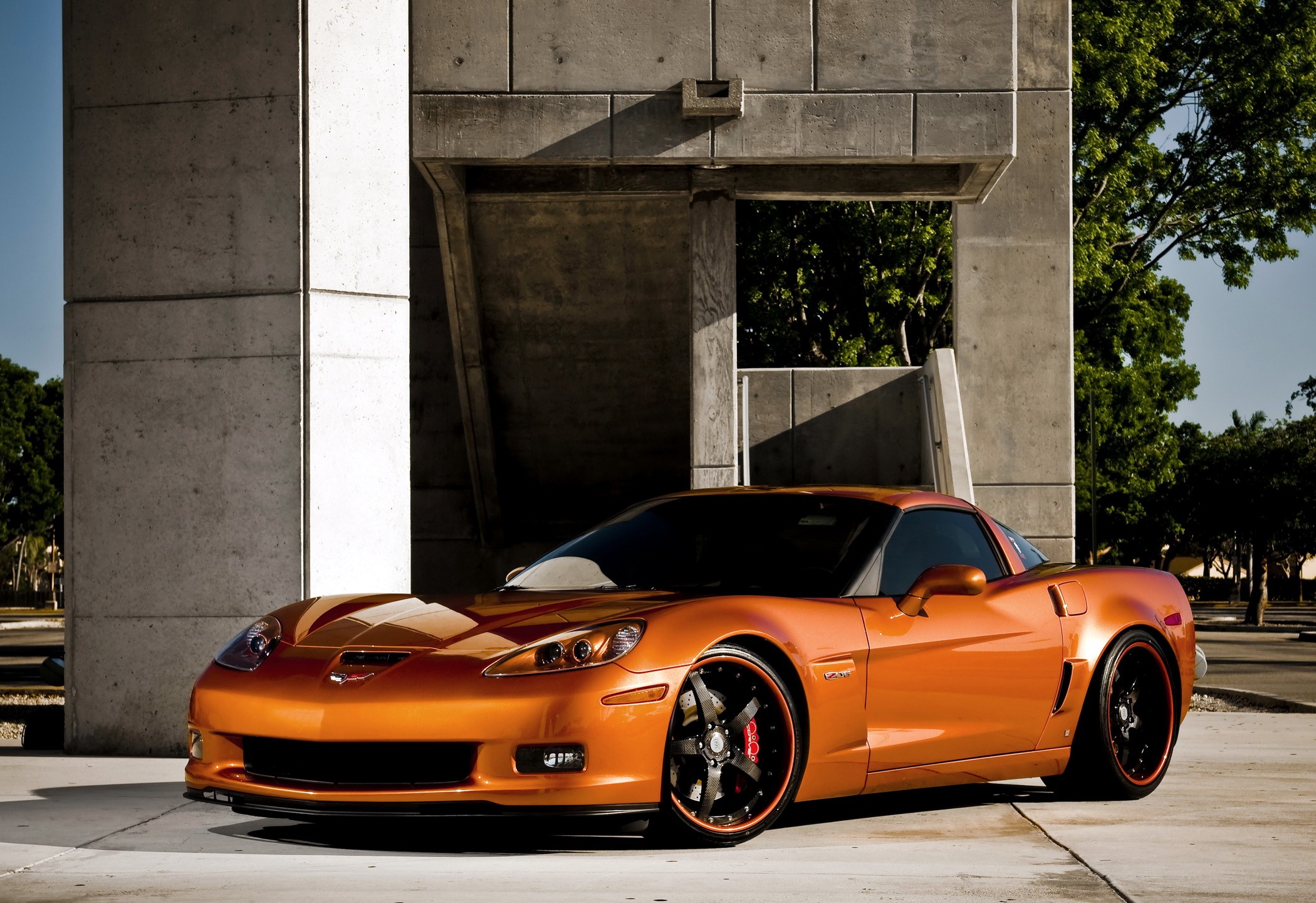 Orange Chevrolet Corvette parked near concrete structure HD Wallpaper