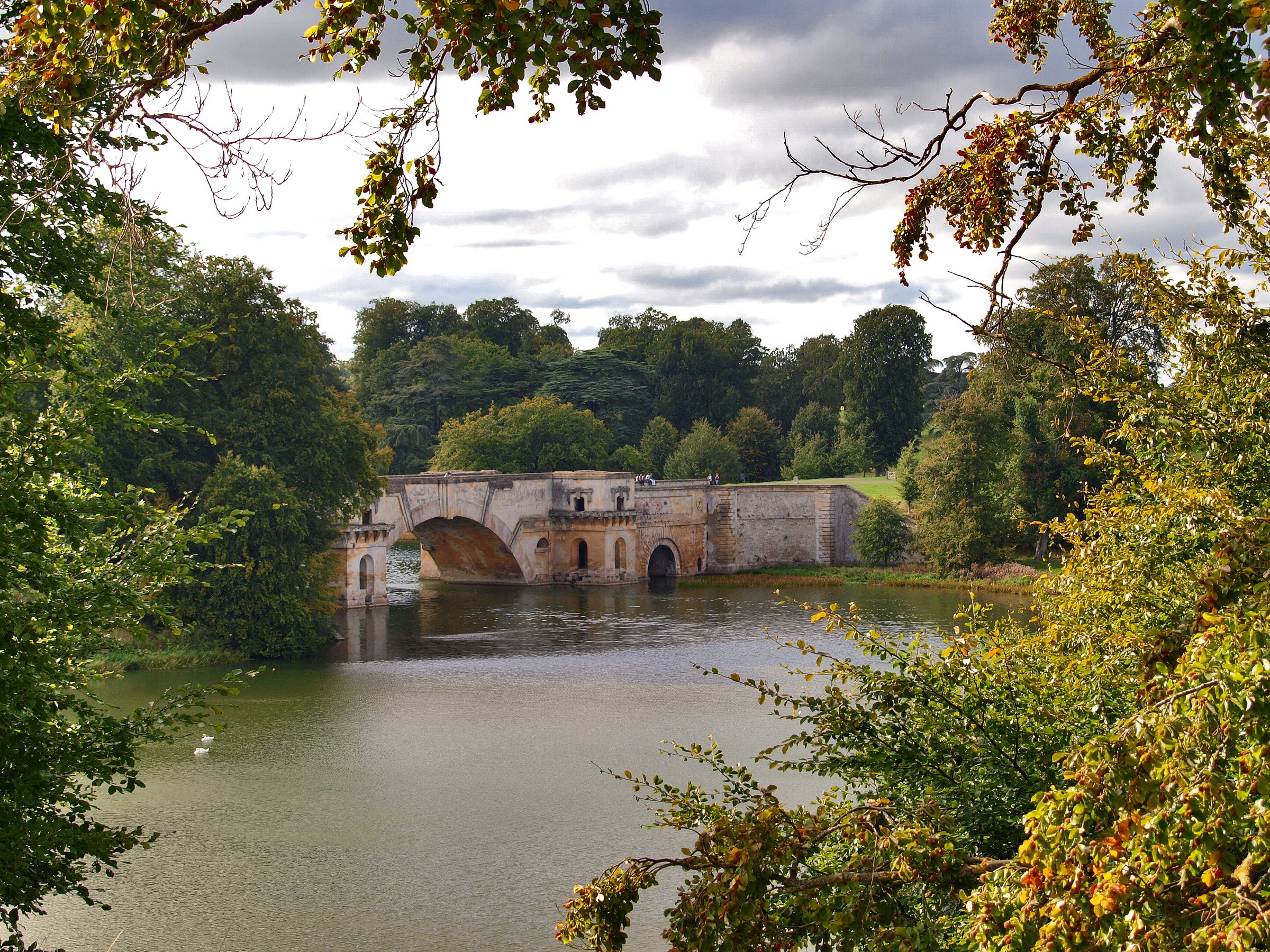 Stone bridge over a lake surrounded by trees HD Wallpaper