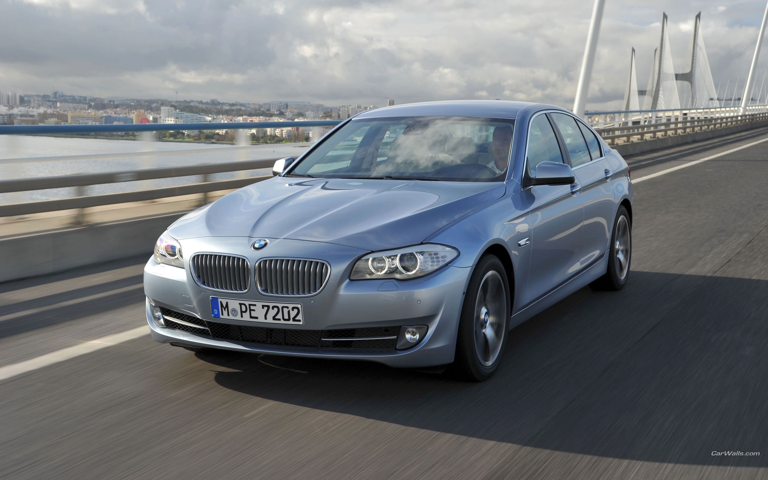 Silver BMW 5 Series driving on a bridge HD Wallpaper