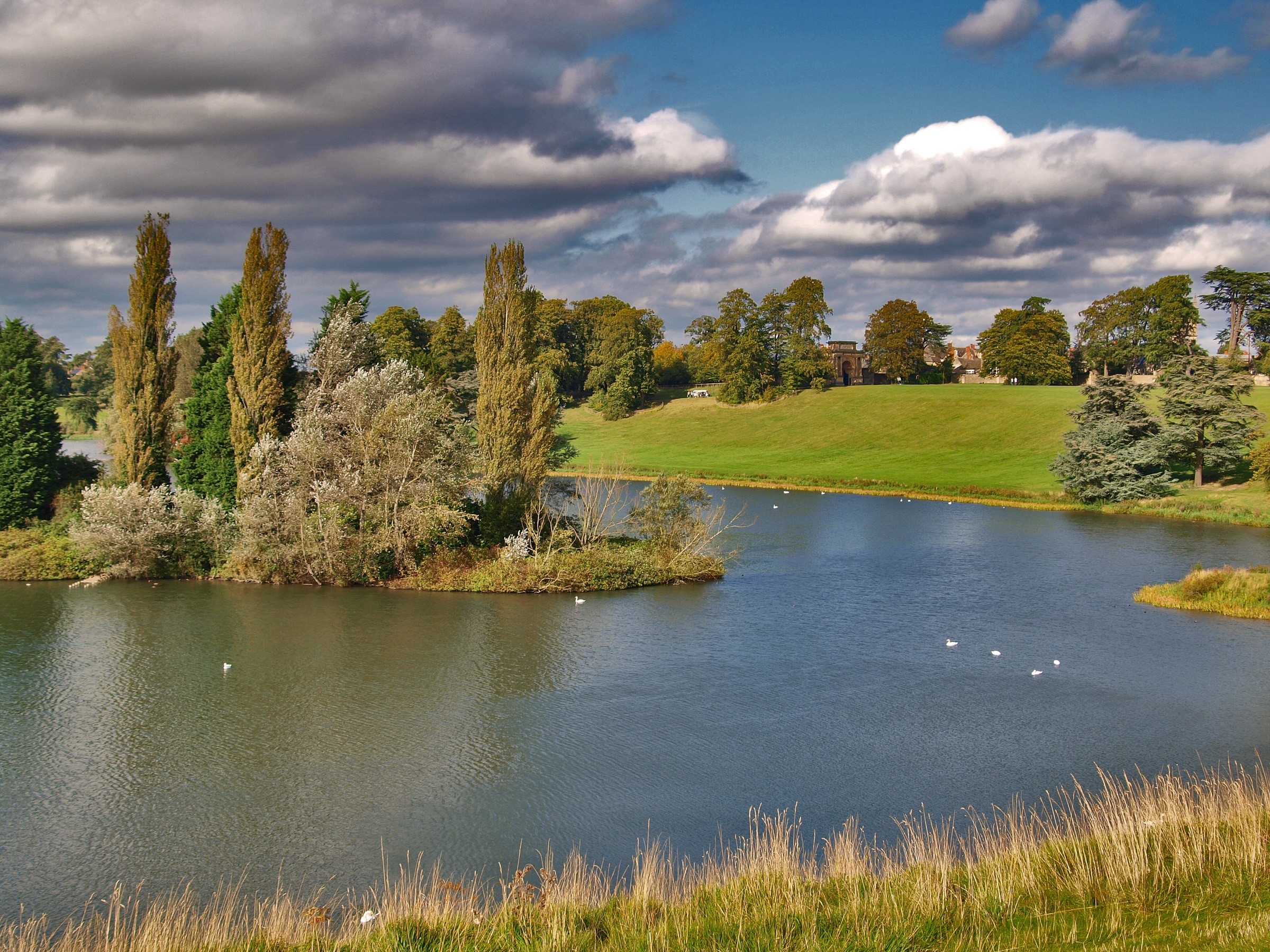 A lake with trees and a building in the background HD Wallpaper