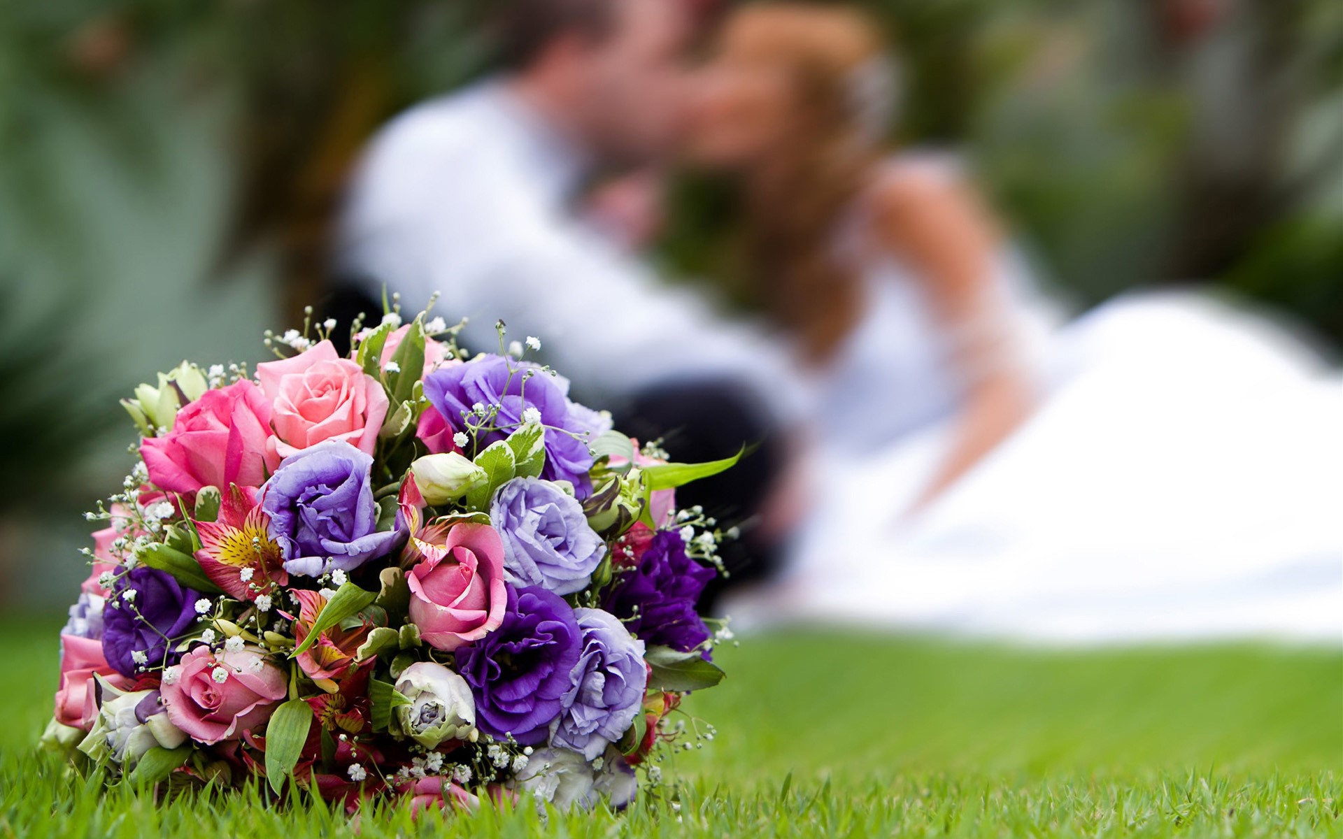 Wedding bouquet with couple kissing in background HD Wallpaper