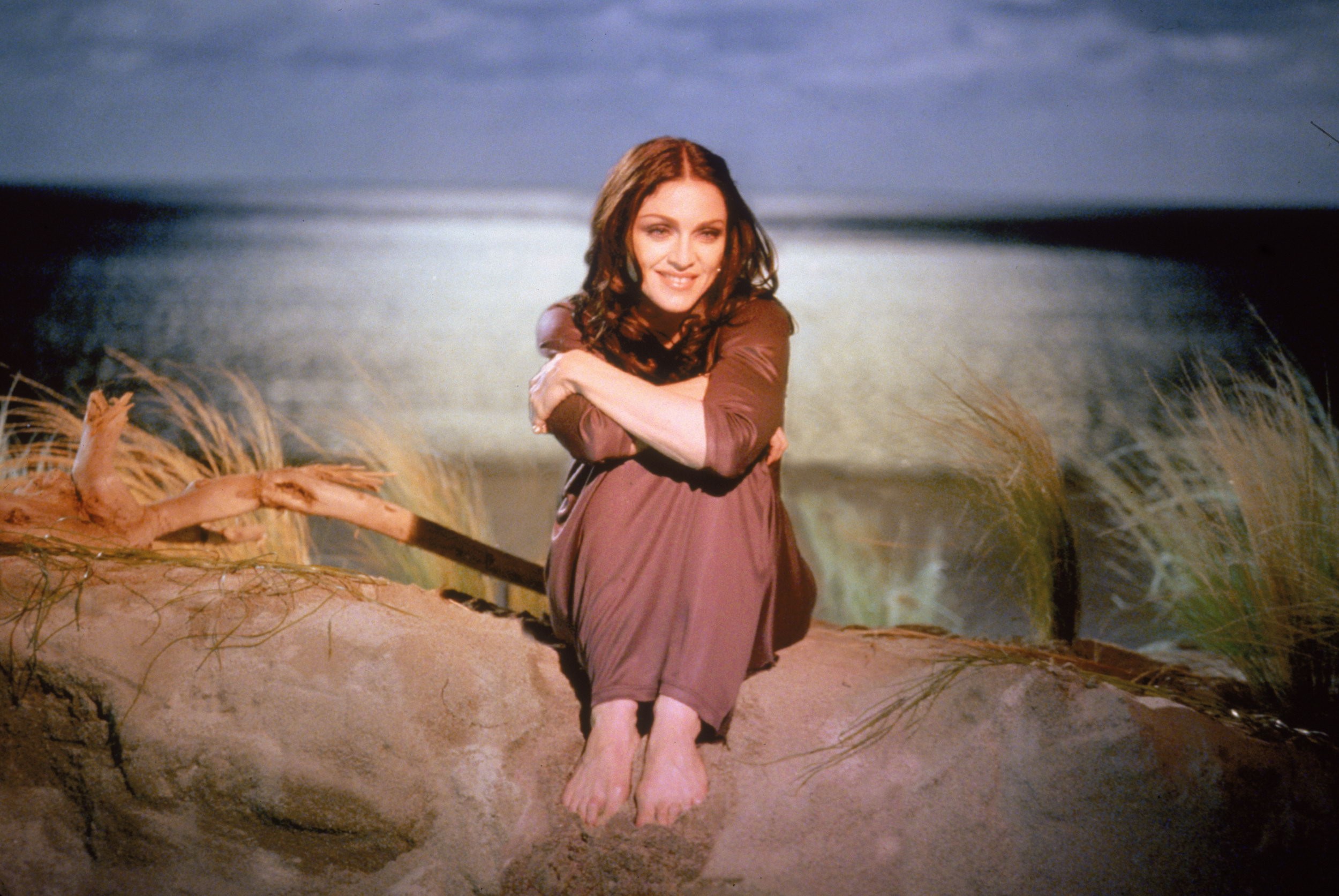Madonna sitting on a sandy shore HD Wallpaper