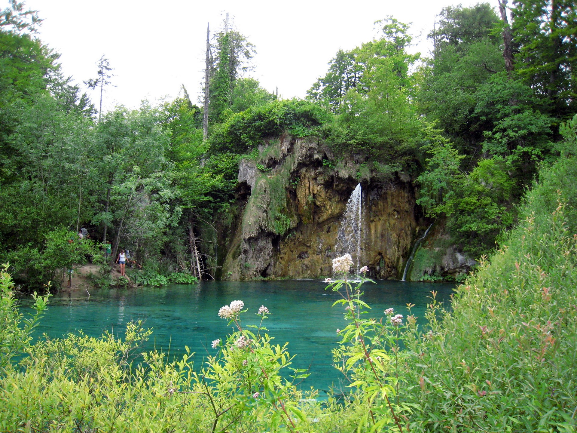 Waterfall cascading into turquoise lake in Plitvice Lakes National Park, Croatia HD Wallpaper