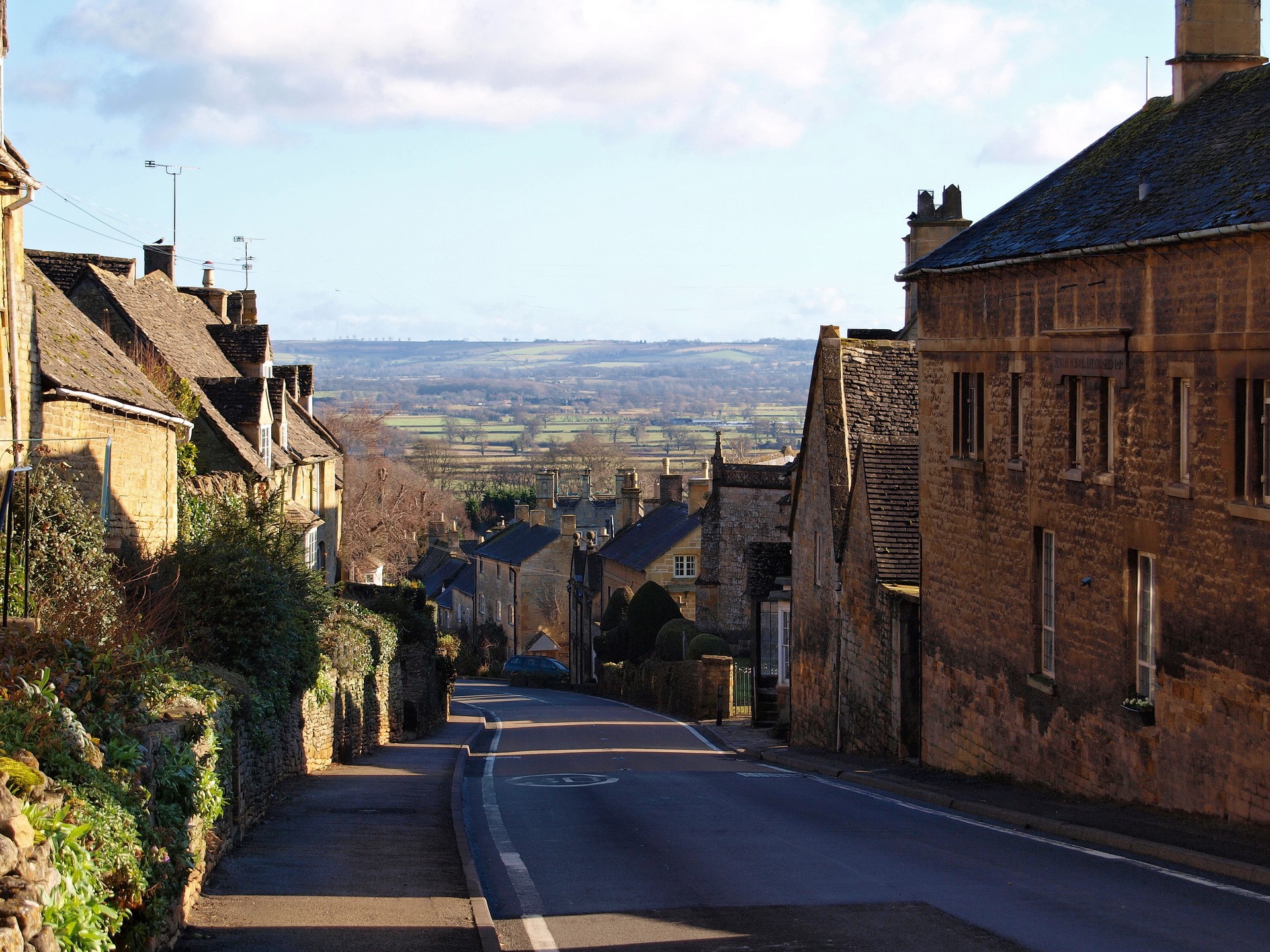 Village street in the United Kingdom with rolling hills in the distance HD Wallpaper