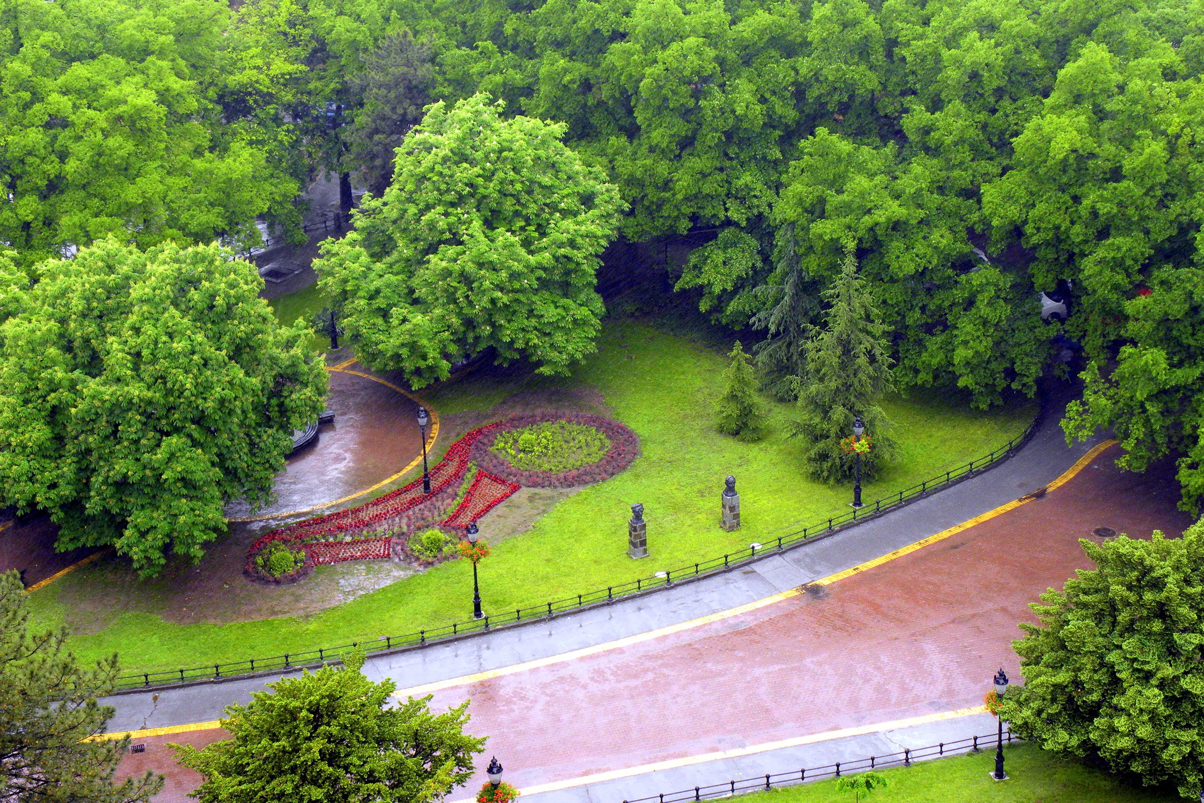 A park with trees, flower beds, and a path HD Wallpaper