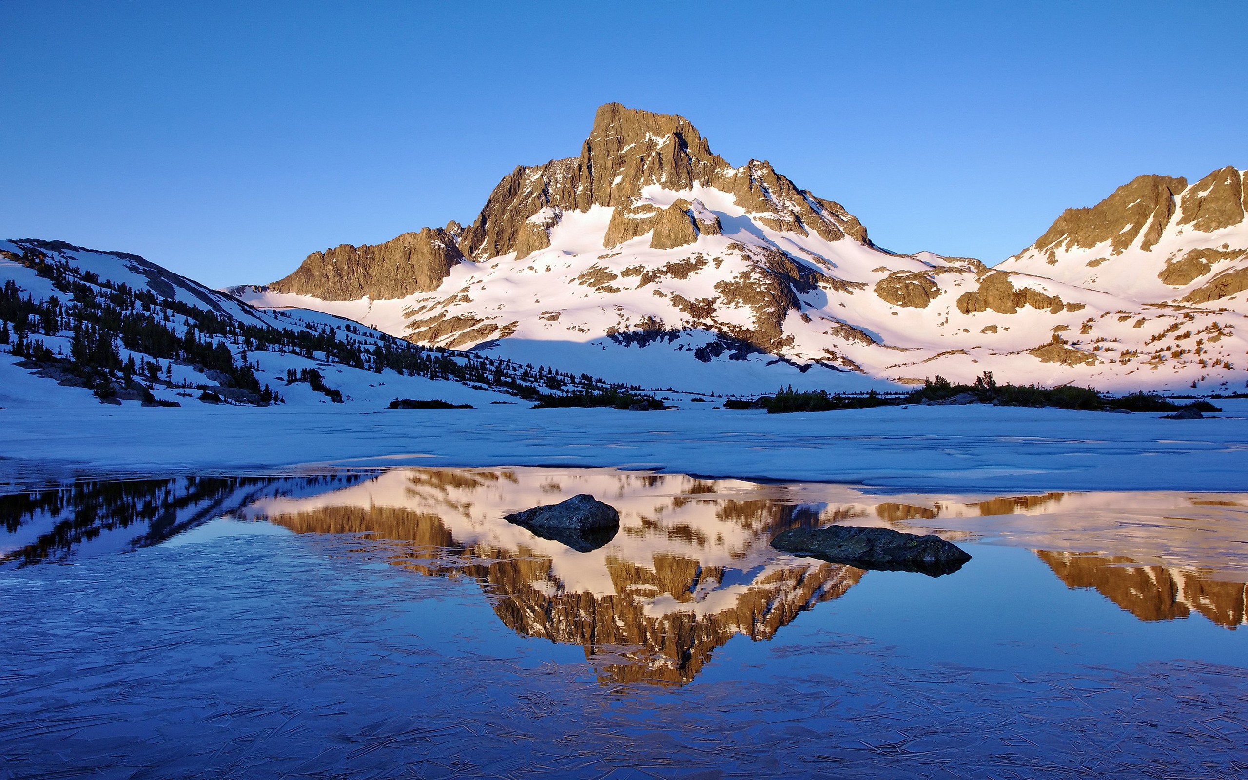 Snow-covered mountains reflected in a frozen lake HD Wallpaper