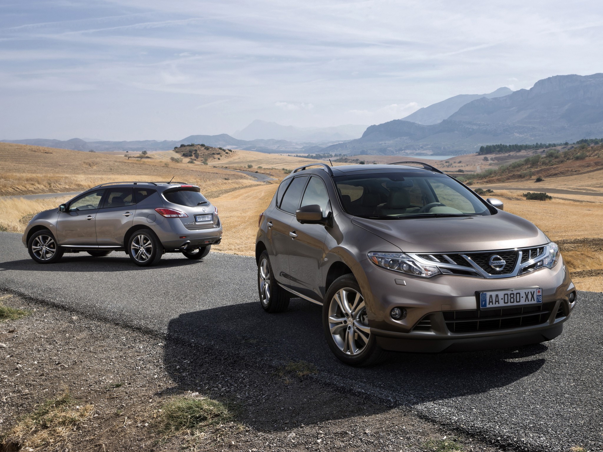 Two Nissan Murano SUVs on a road in a dry landscape HD Wallpaper