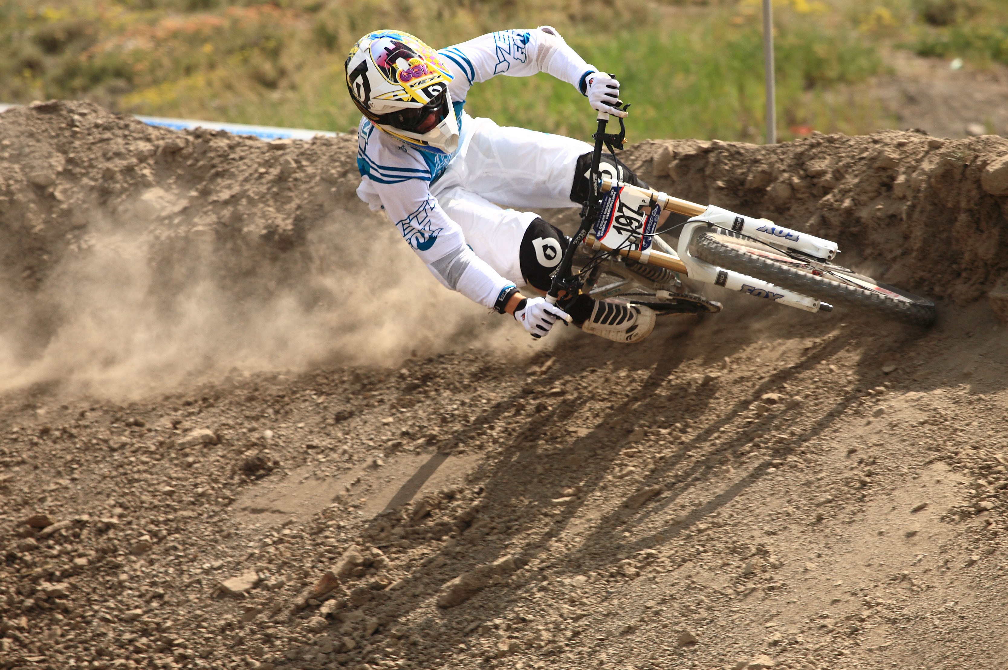 Downhill mountain biker in action on a dirt track HD Wallpaper