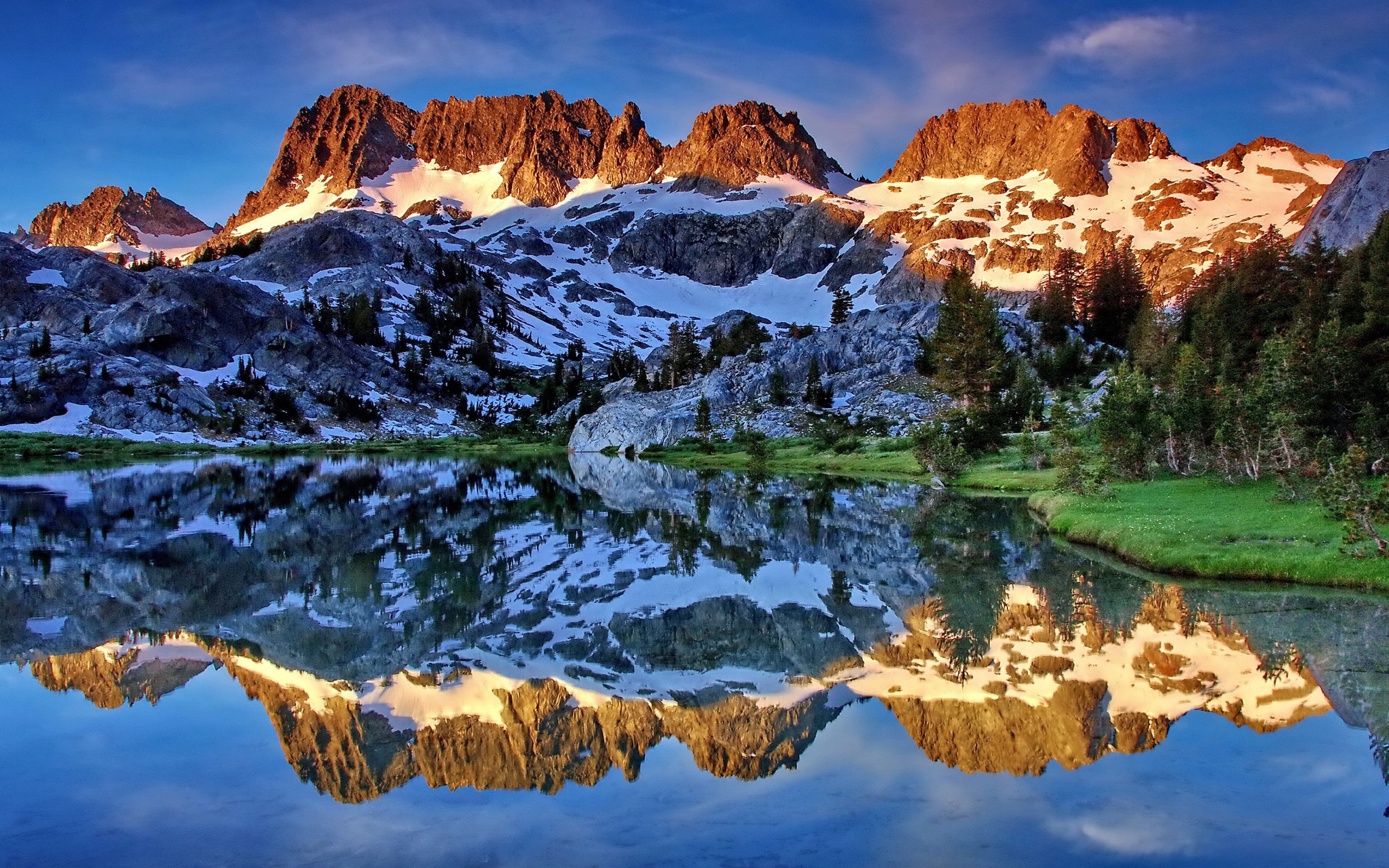 Snow-capped mountains reflected in a calm lake at sunrise HD Wallpaper