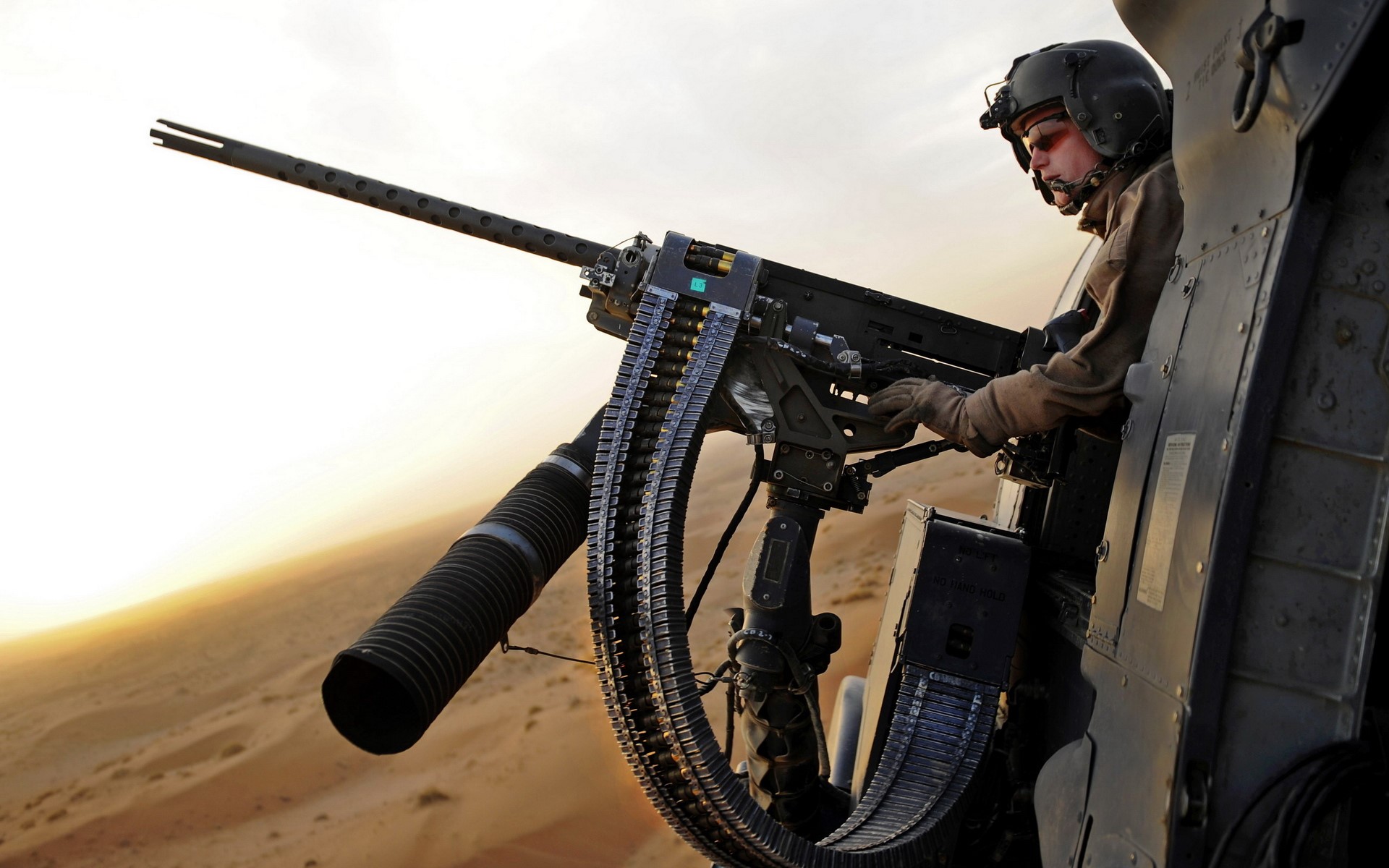 Soldier operating a mounted machine gun from a helicopter HD Wallpaper